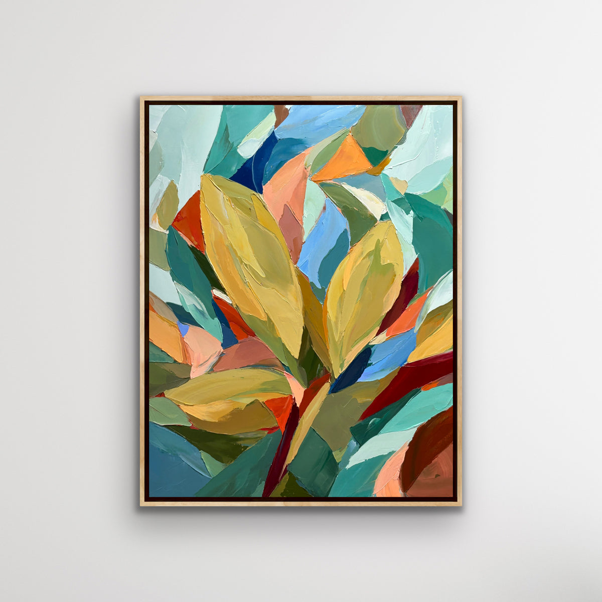 Framed abstract art with colourful leaves on a white wall executed in rich palette knife strokes.