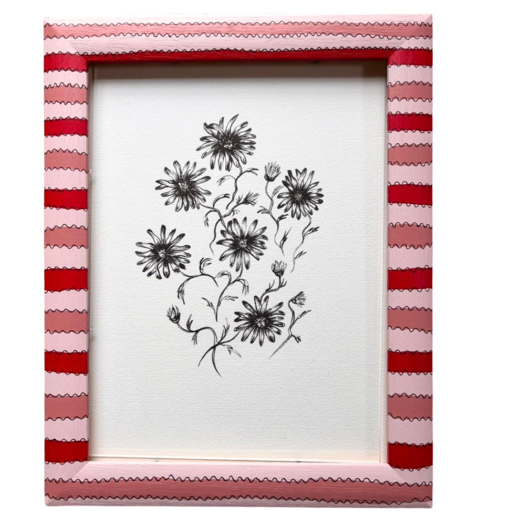 Framed artwork with floral design inside a striped pink and red frame on a white background