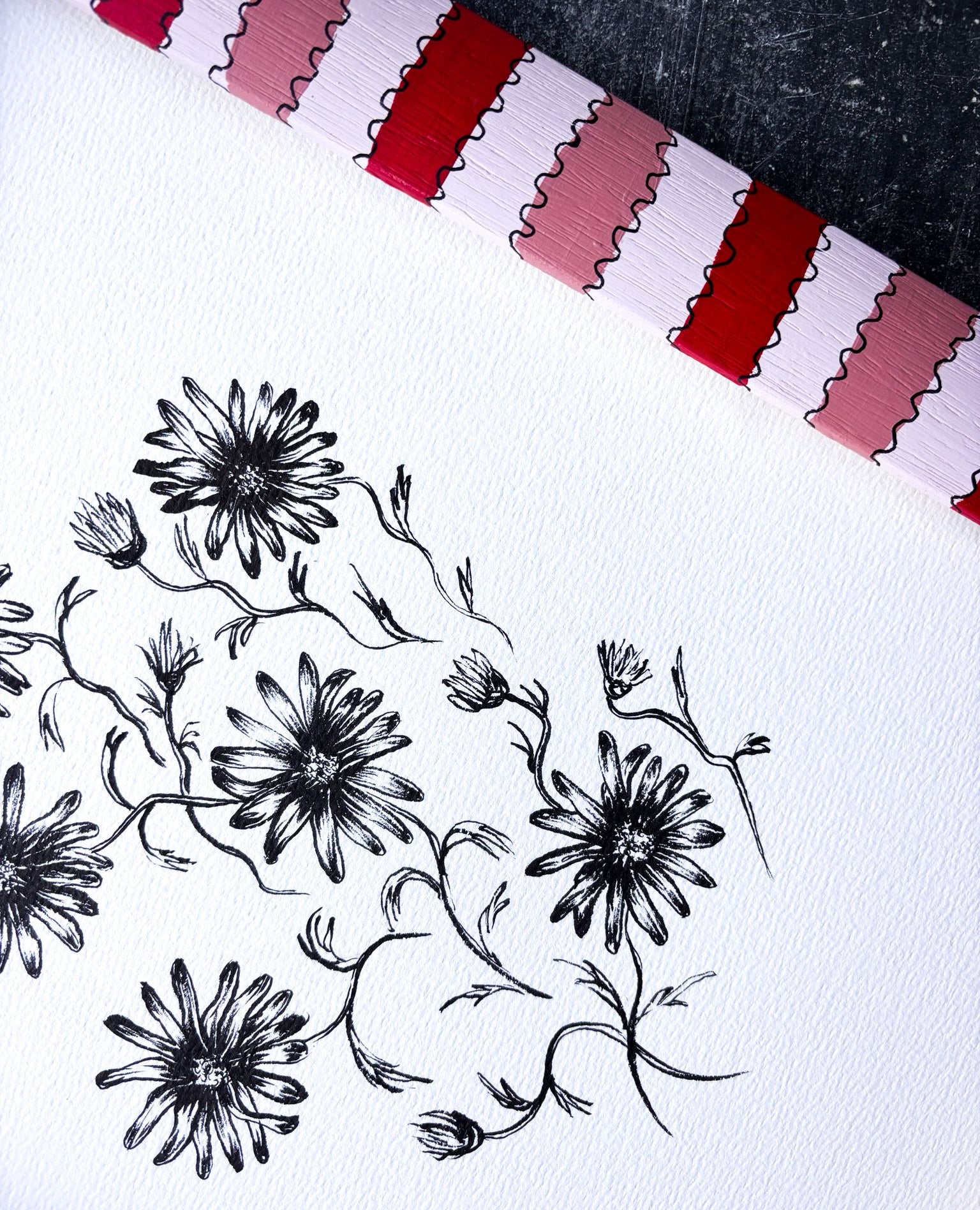 Black floral doodles on white paper with a red and white striped border.