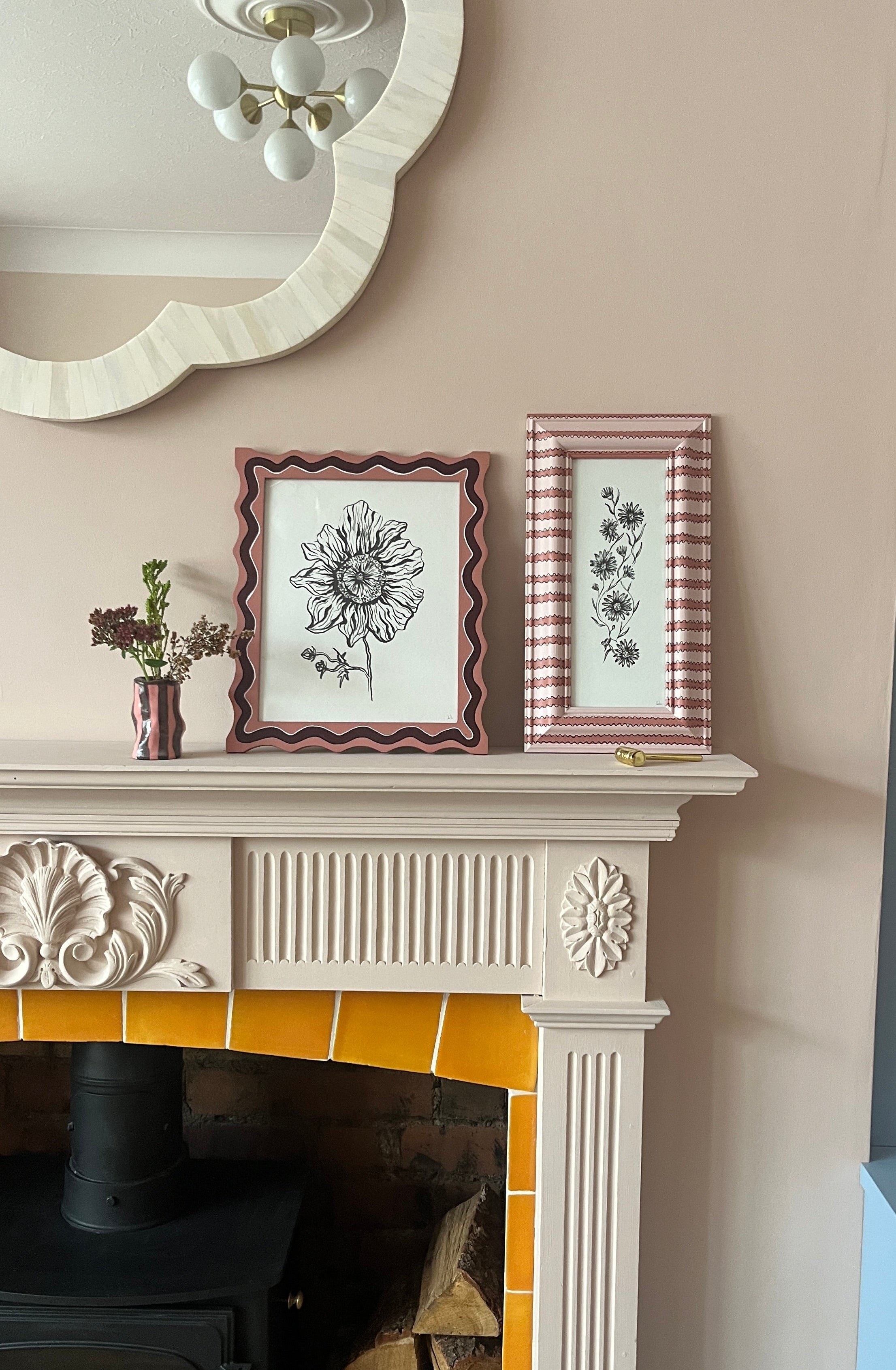 Decorative fireplace with framed artwork and a mirror above it.