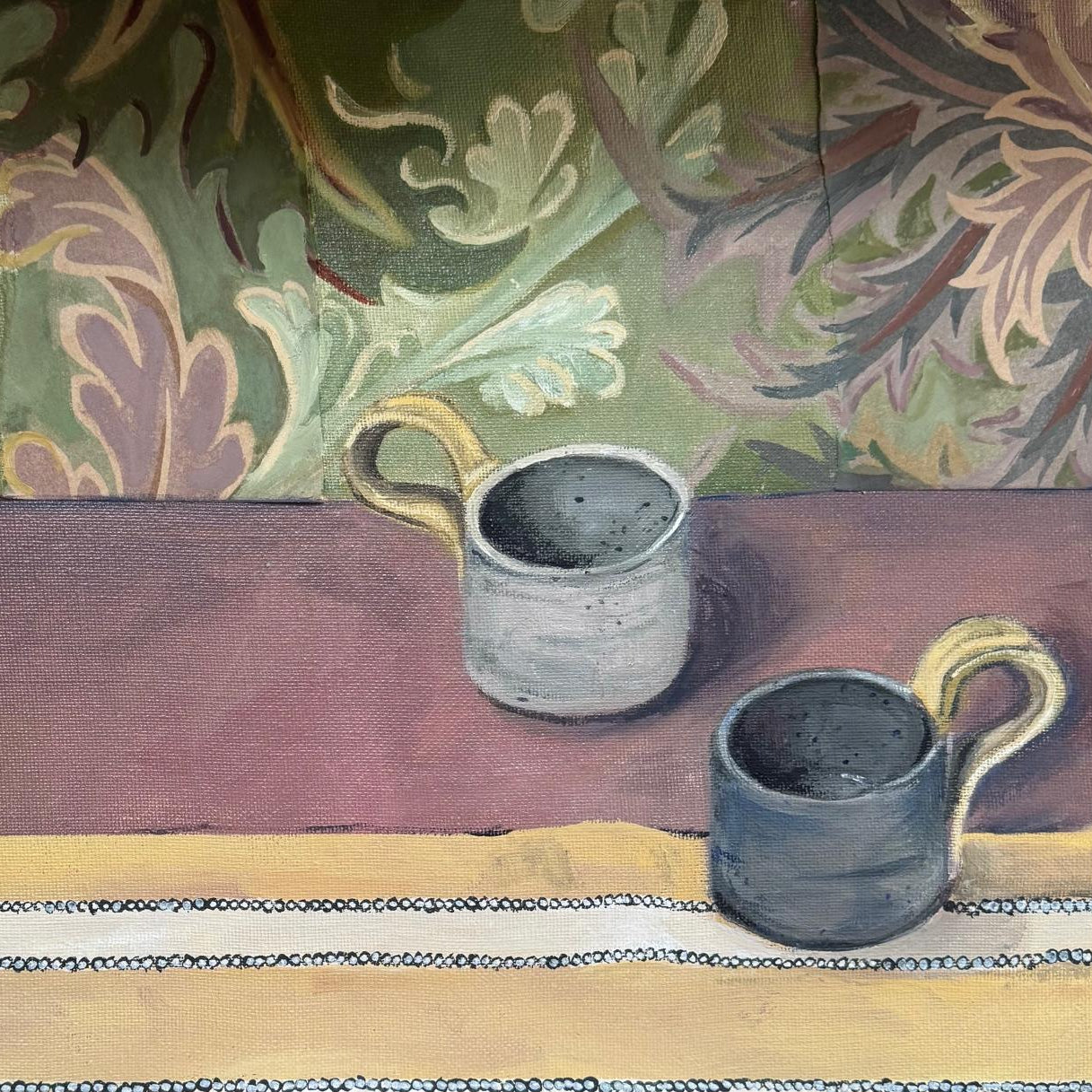 Two Mugs sat on tabel with pattered floral wallpaper in background
