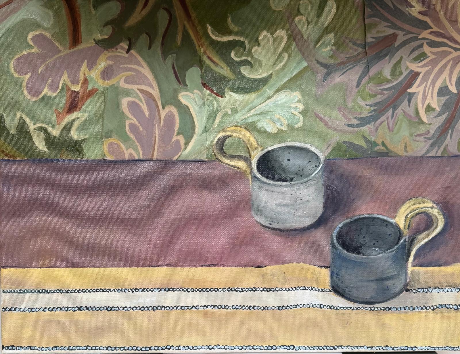 Two Mugs sat on table with floral wallpaper in the backgroubd