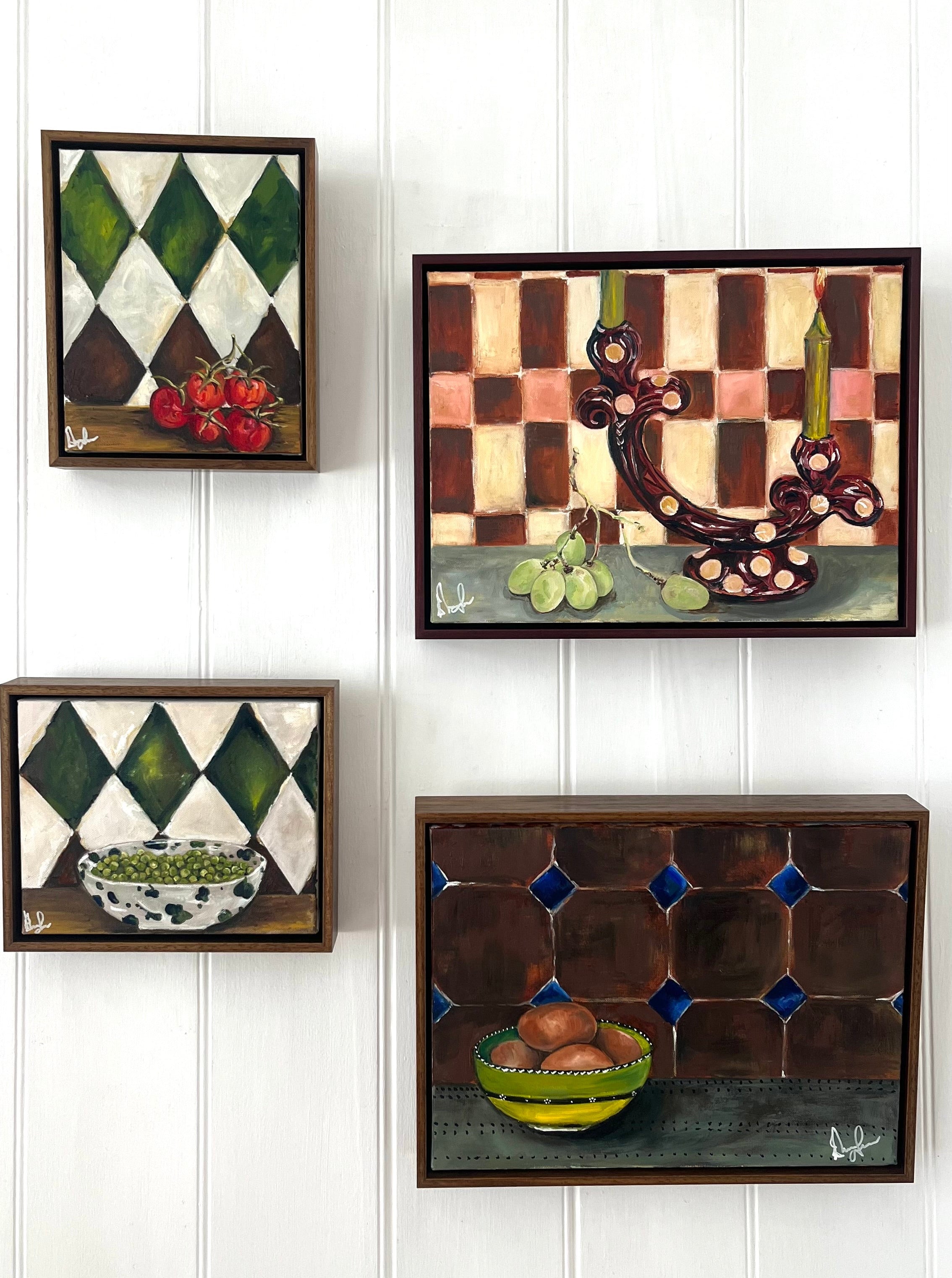 Four framed artworks on a white paneled wall