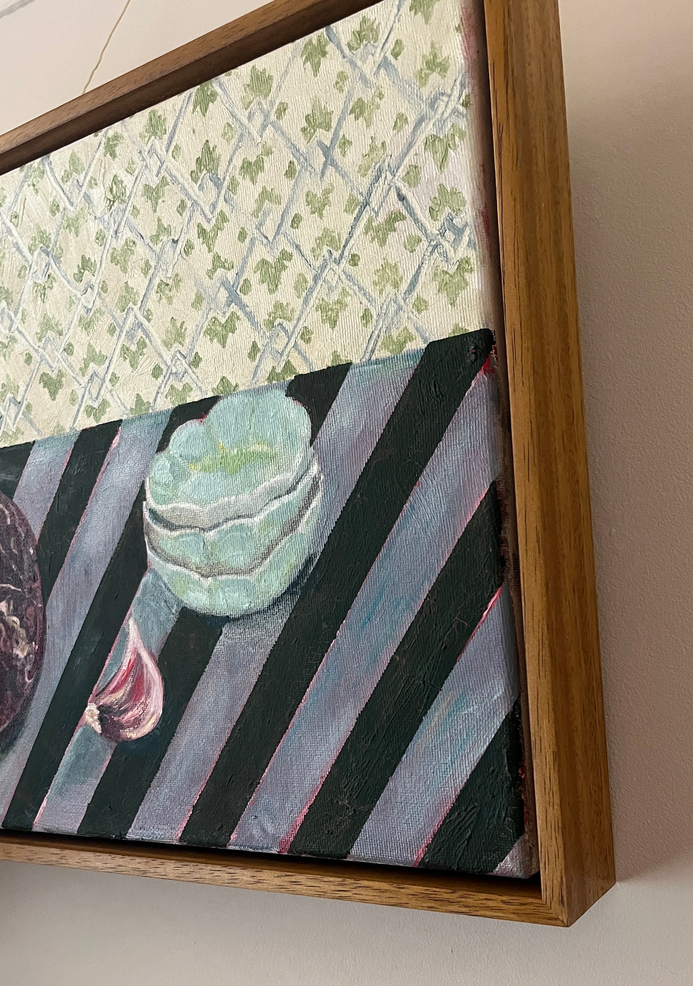 Framed Emma Gurner artwork with a patterned background and a central tiered bowls on stripe tablecloth