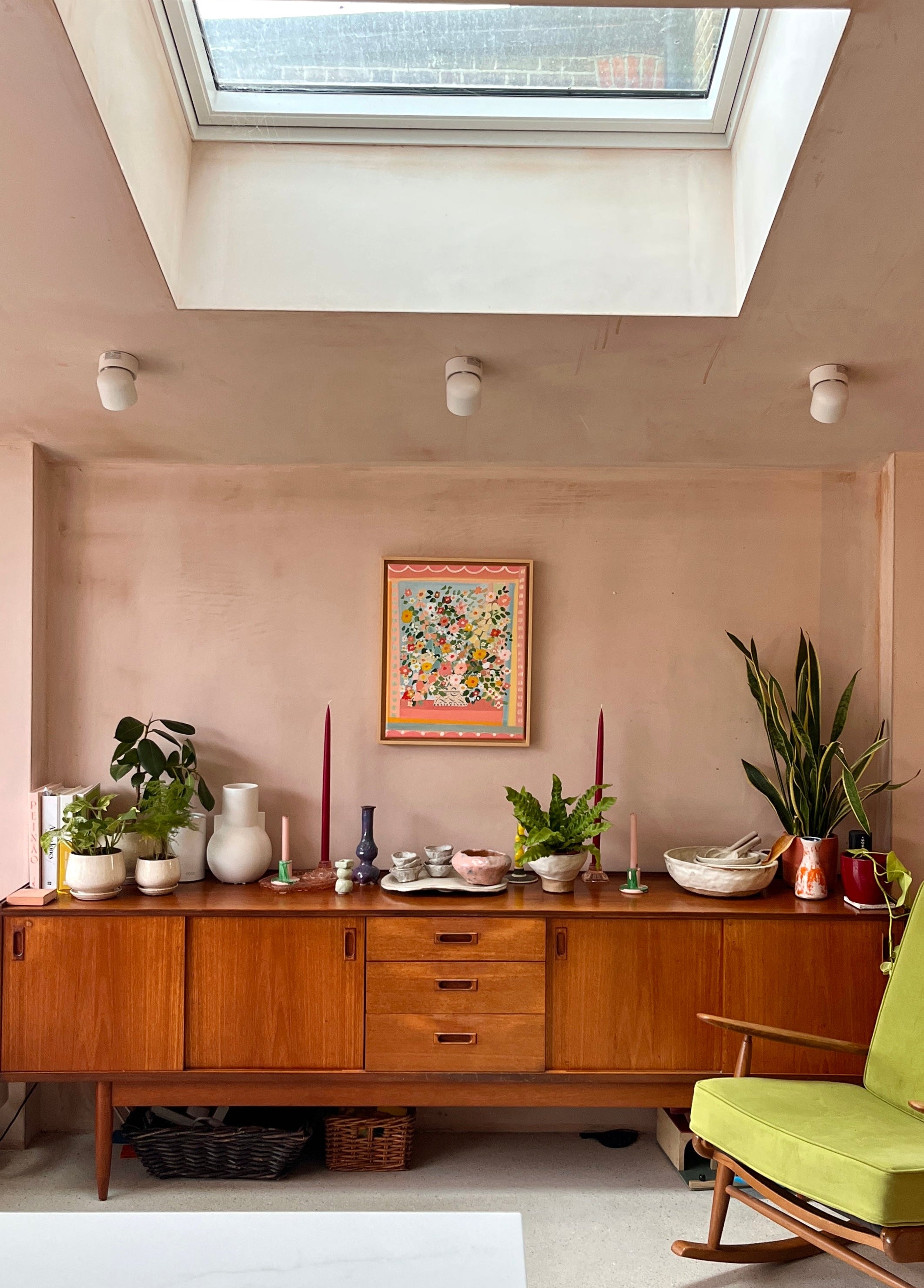 Living room with wooden sideboard, green chair, and skylight.