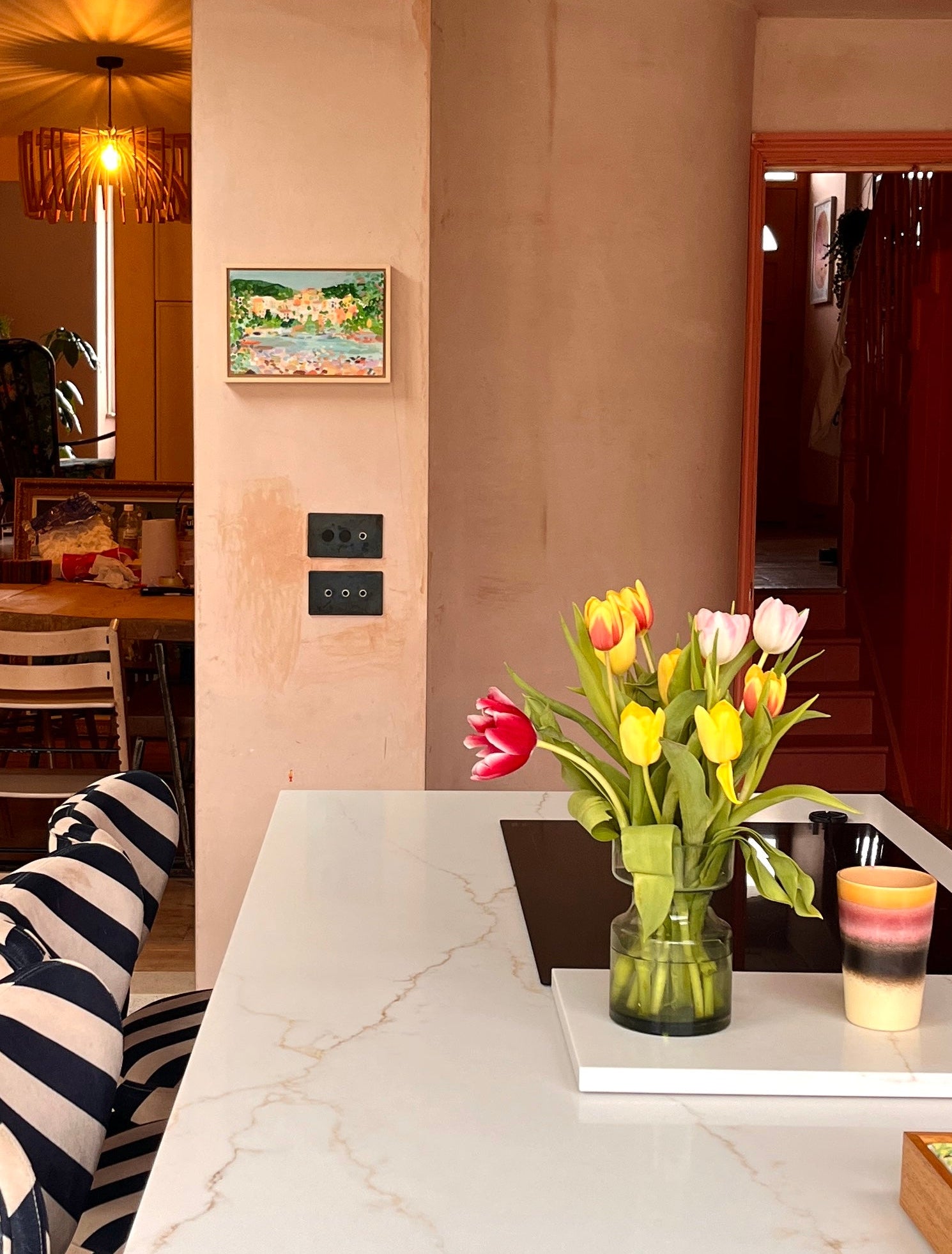 Art in Kitchen next to a counter top with a vase and tulips.