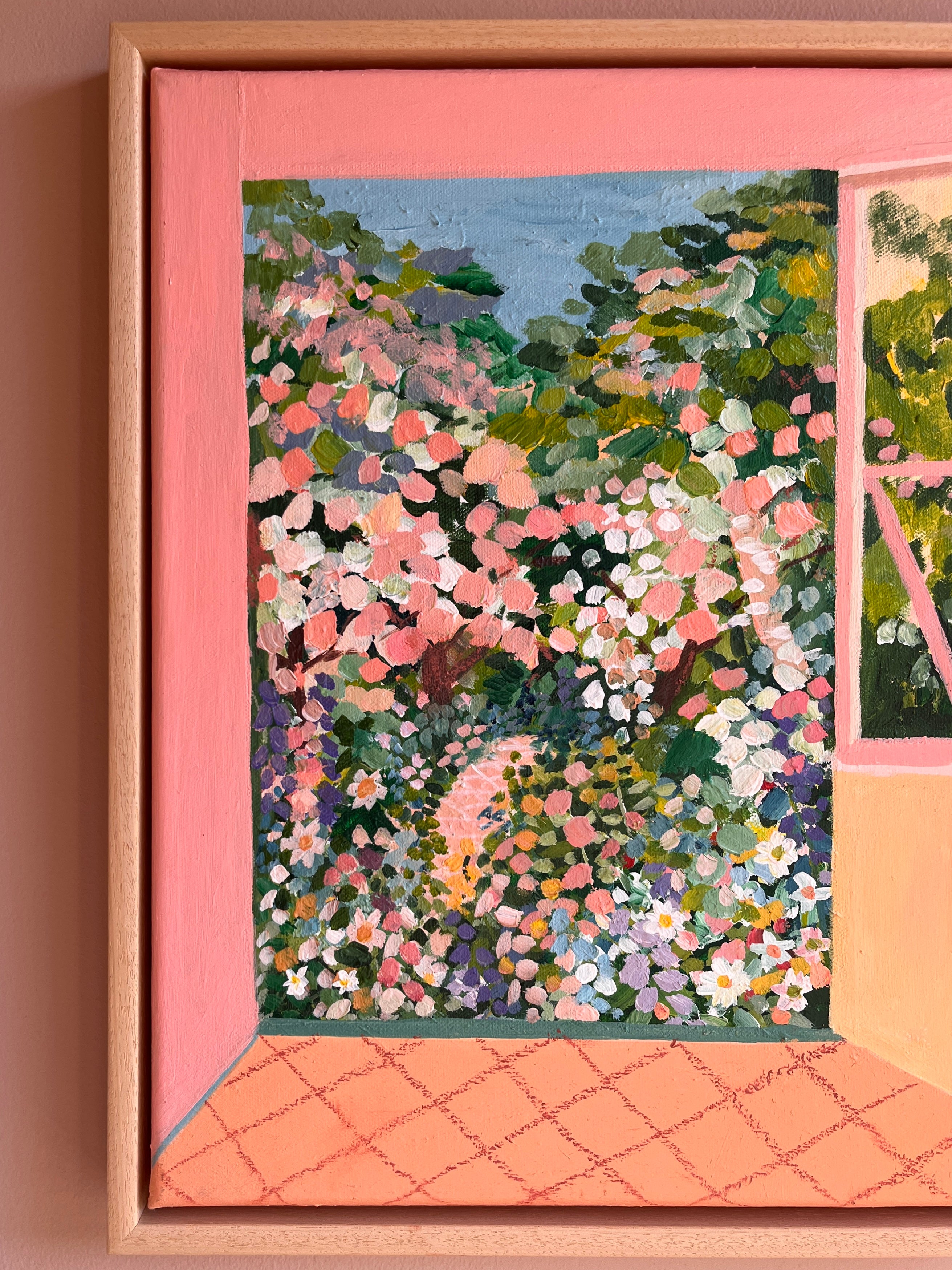 Framed artwork of a garden scene with flowers and trees on a pink wall.