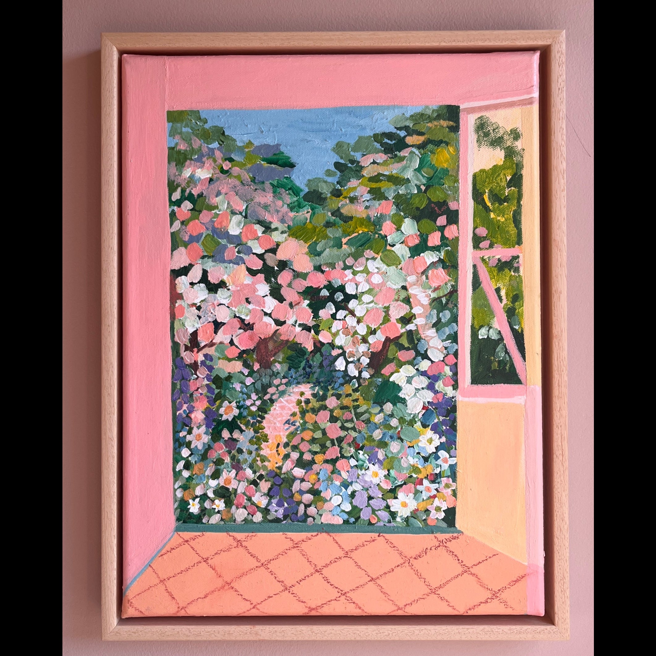 Framed artwork of a garden scene with pink and green tones on a pink wall.