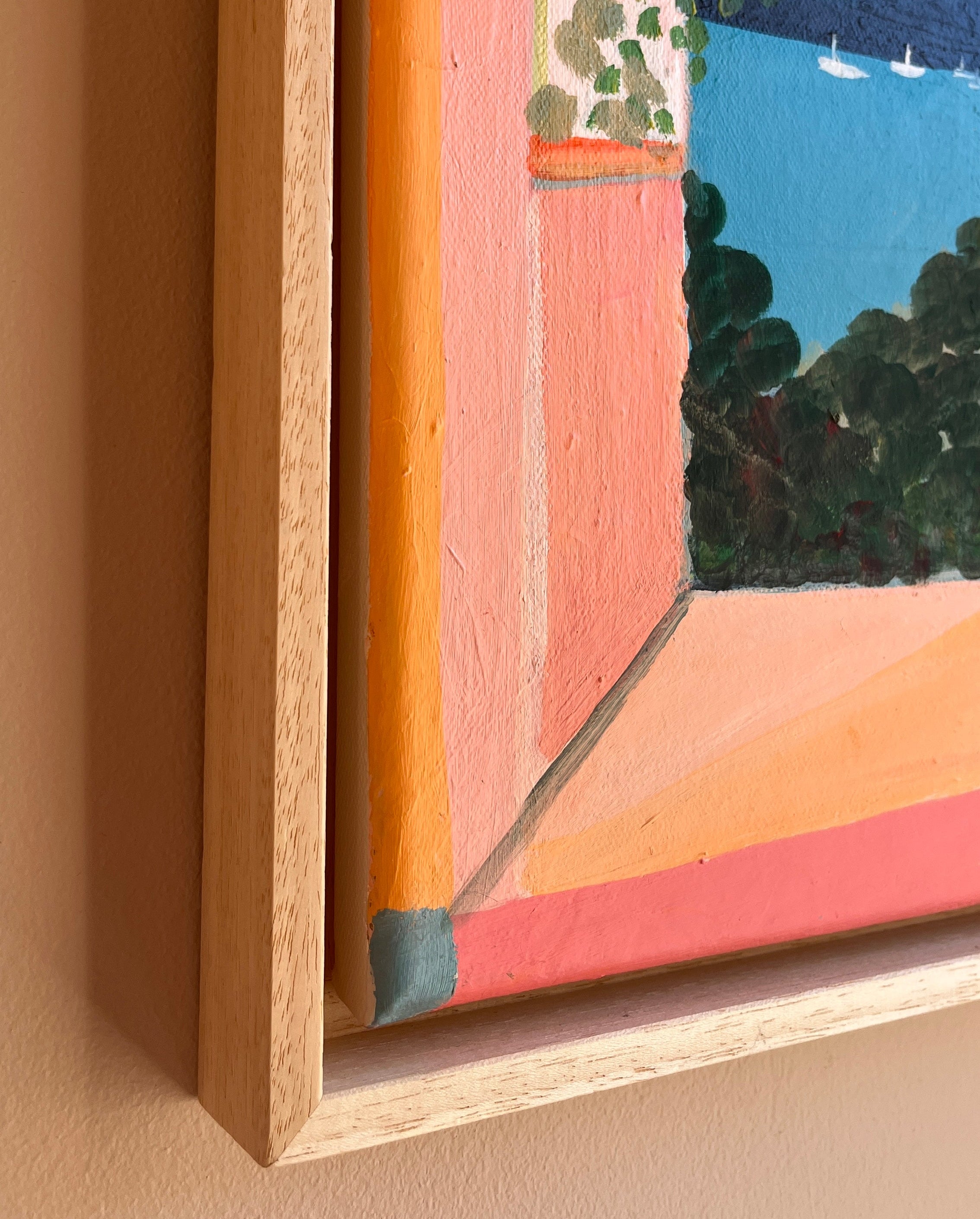 Framed abstract painting with colorful landscape on a beige wall