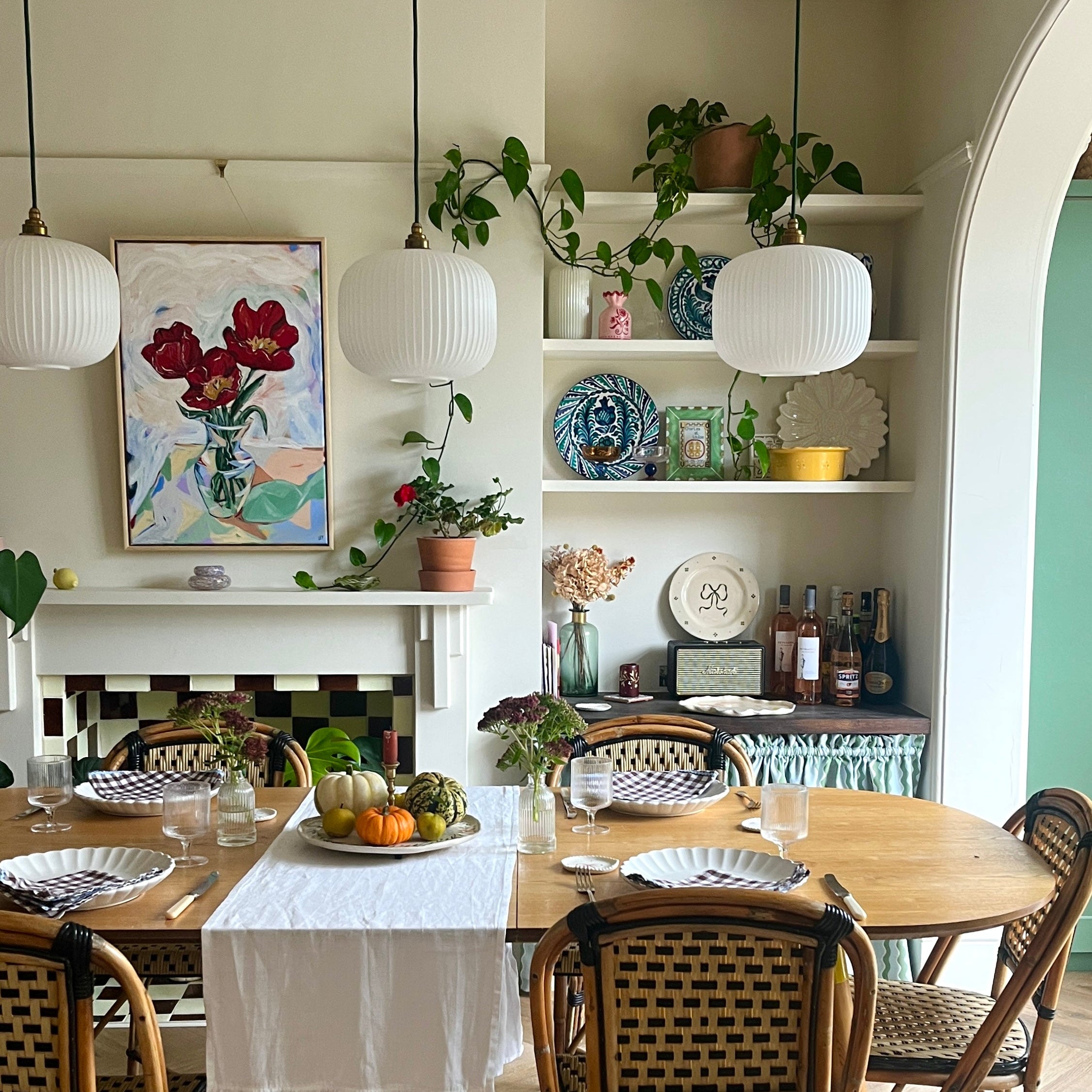 Dining room with wooden table, chairs, and a shelf with decorative items.
