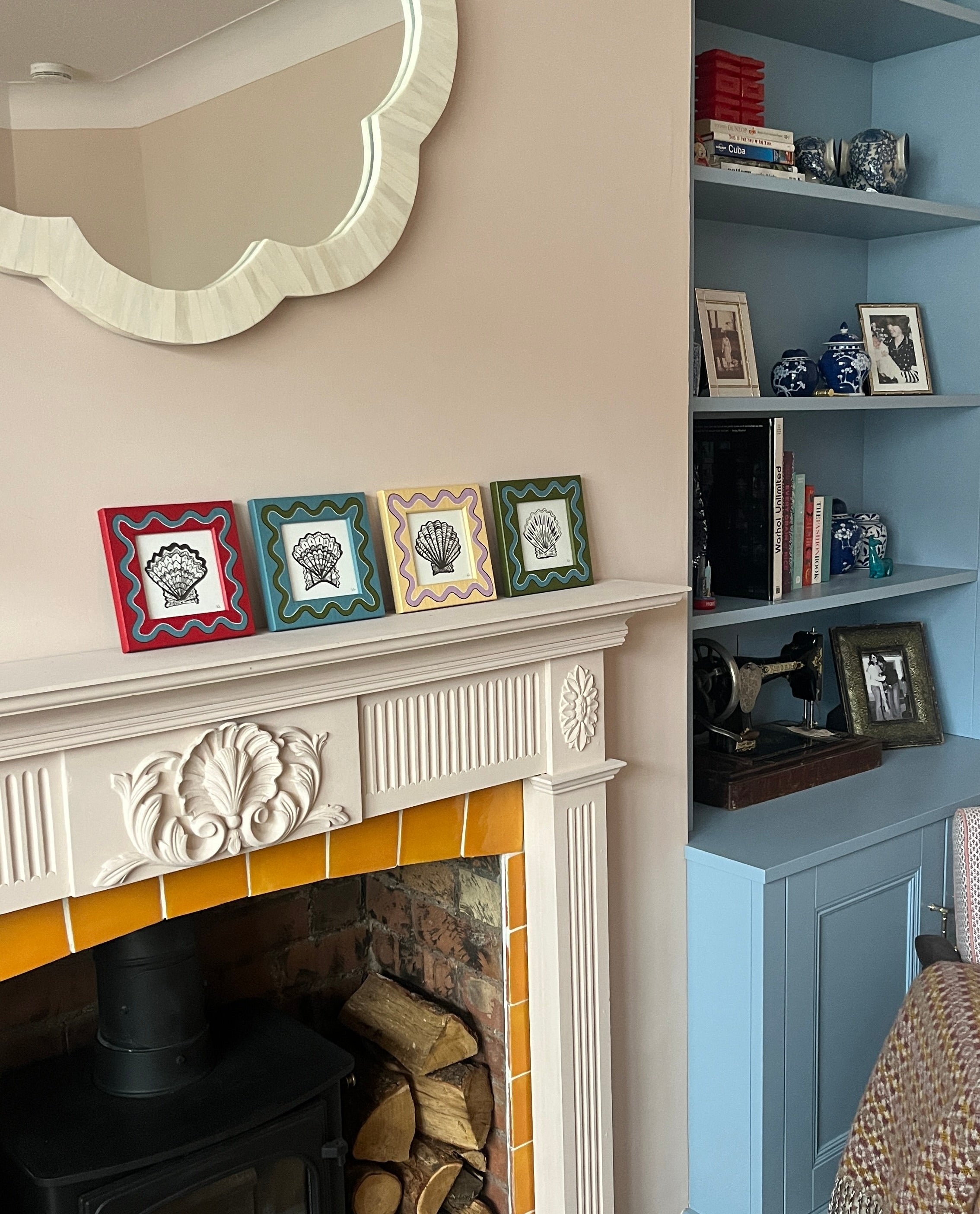 Fireplace with decorative mantel, mirror above, and blue shelving unit with books and decor.