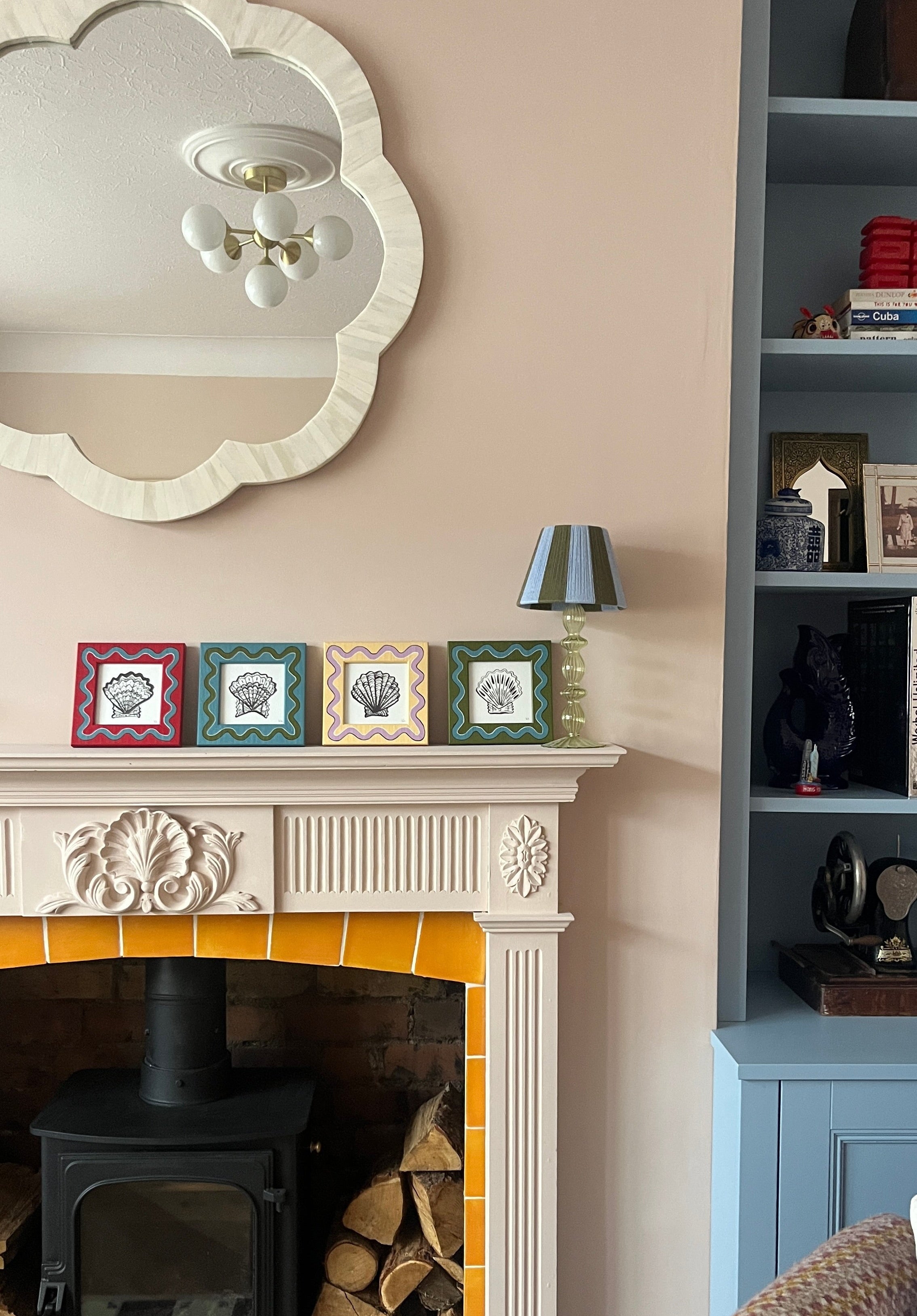 Living room with fireplace, decorative frames, and a mirror.