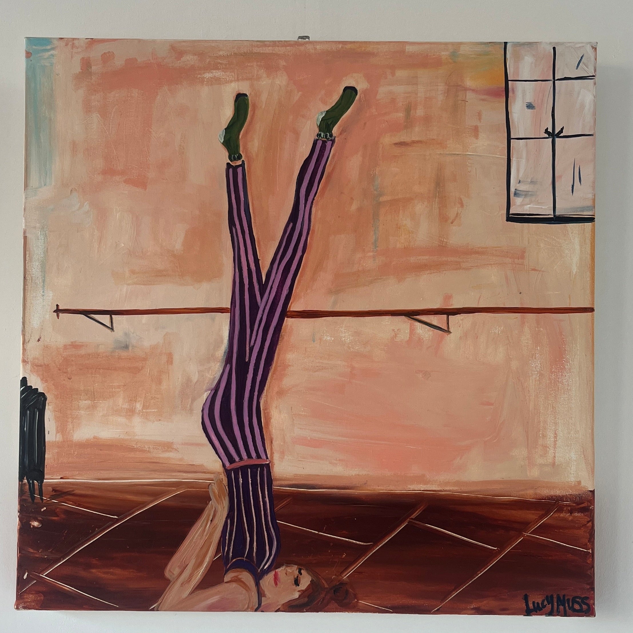 Close up image of a ballerina with her feet up on a bar wearing striped leotard