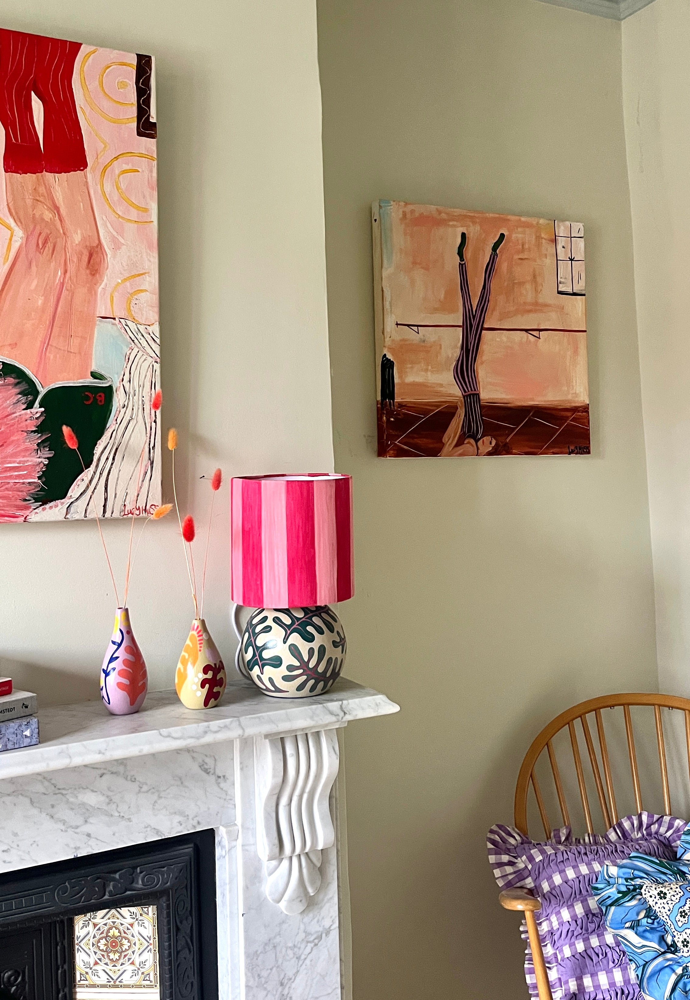 Decorative items on a fireplace mantle with colorful lamp and wall art.