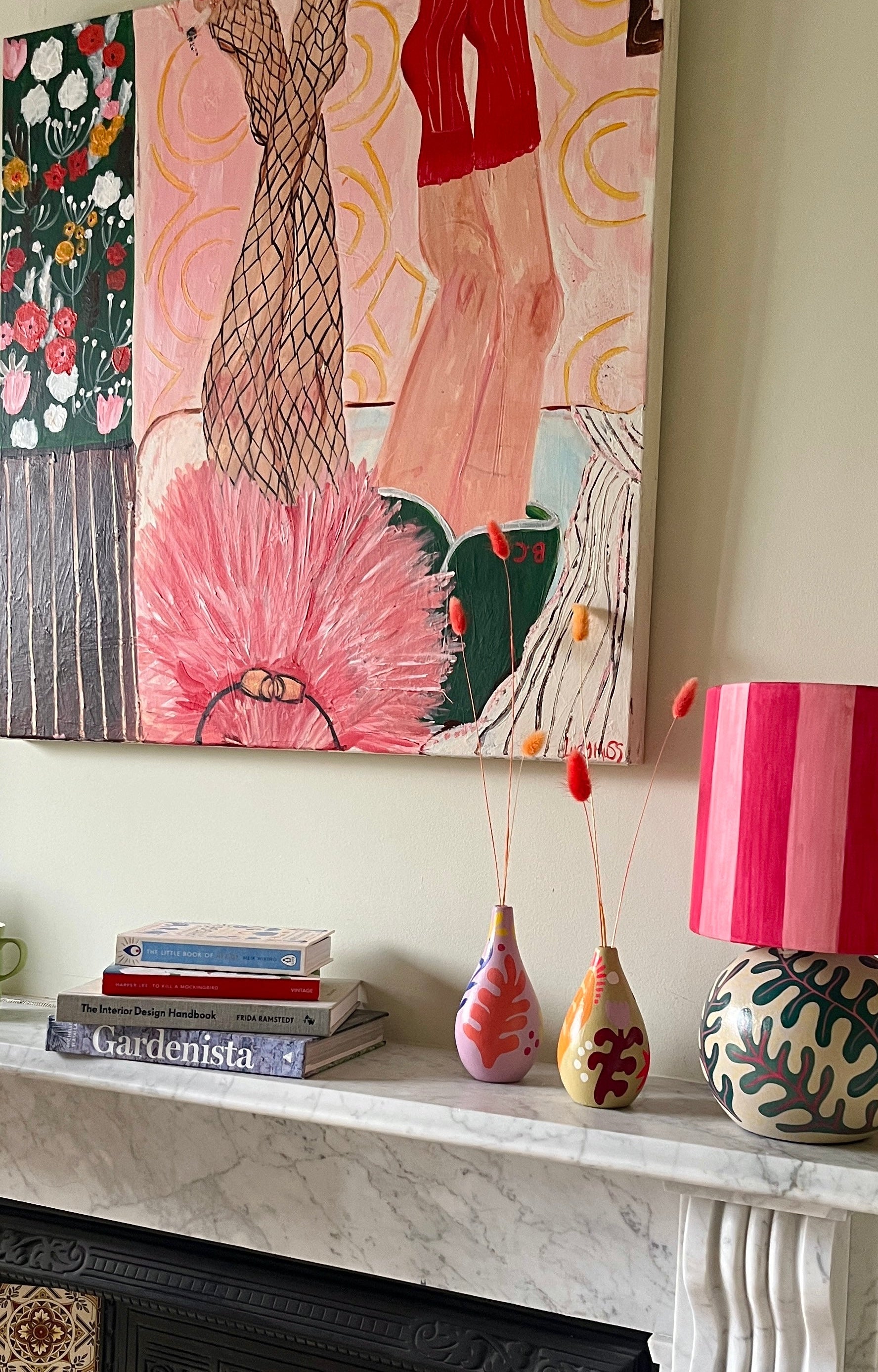 Painting above a marble mantle piece with books and ornaments.