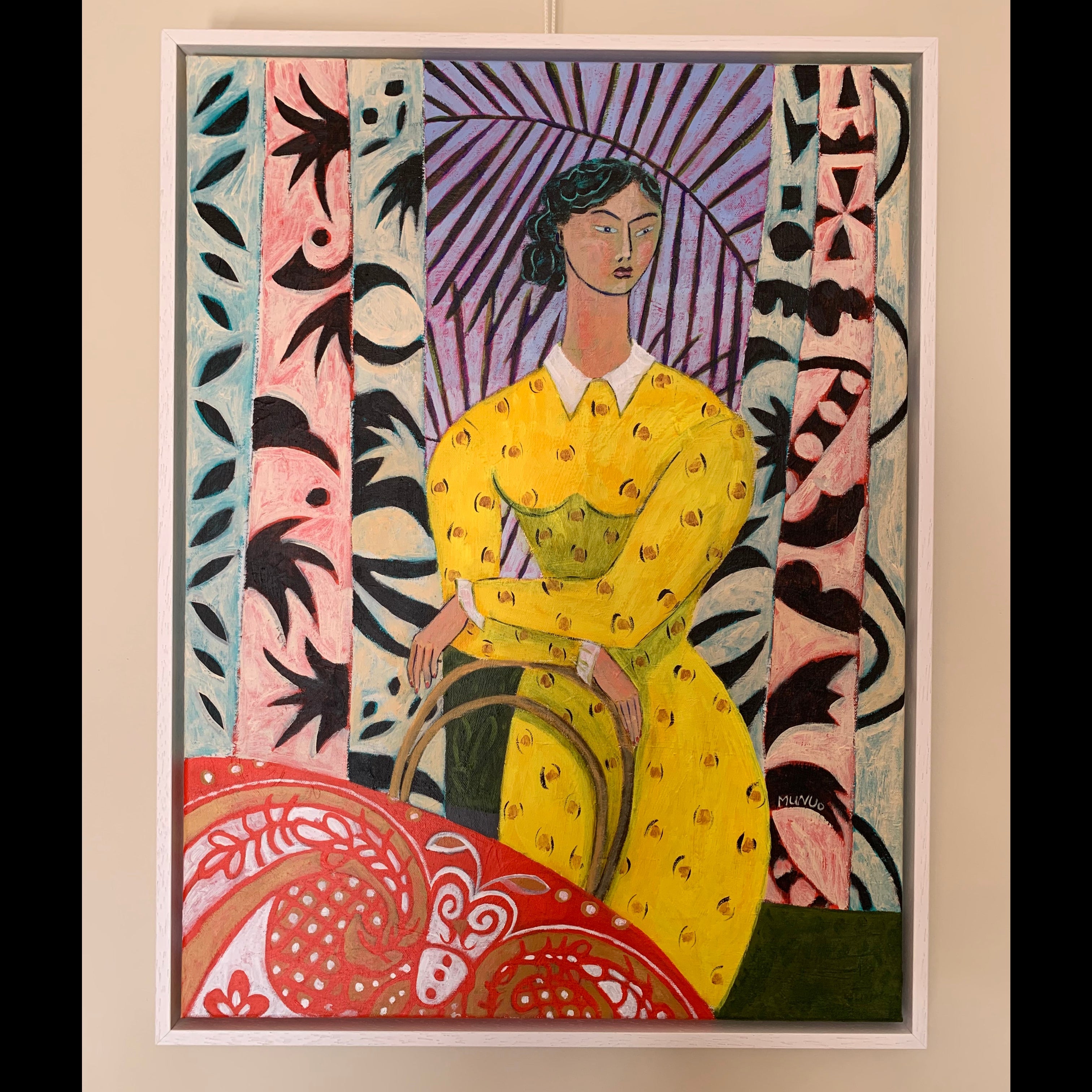 Framed artwork of a woman in a yellow dress with abstract patterns on a beige wall.