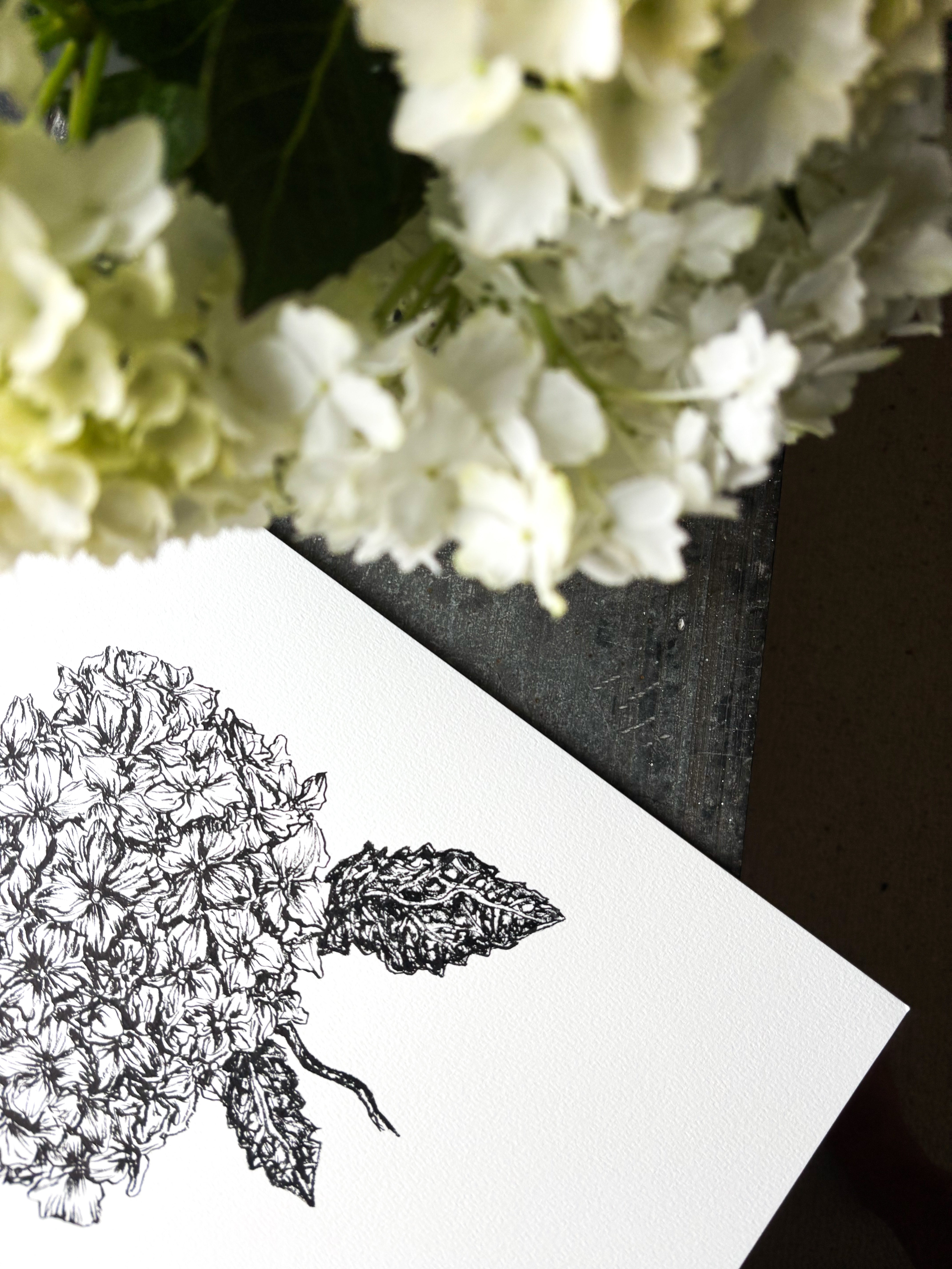 Floral arrangement with a black and white illustration of flowers on a card.