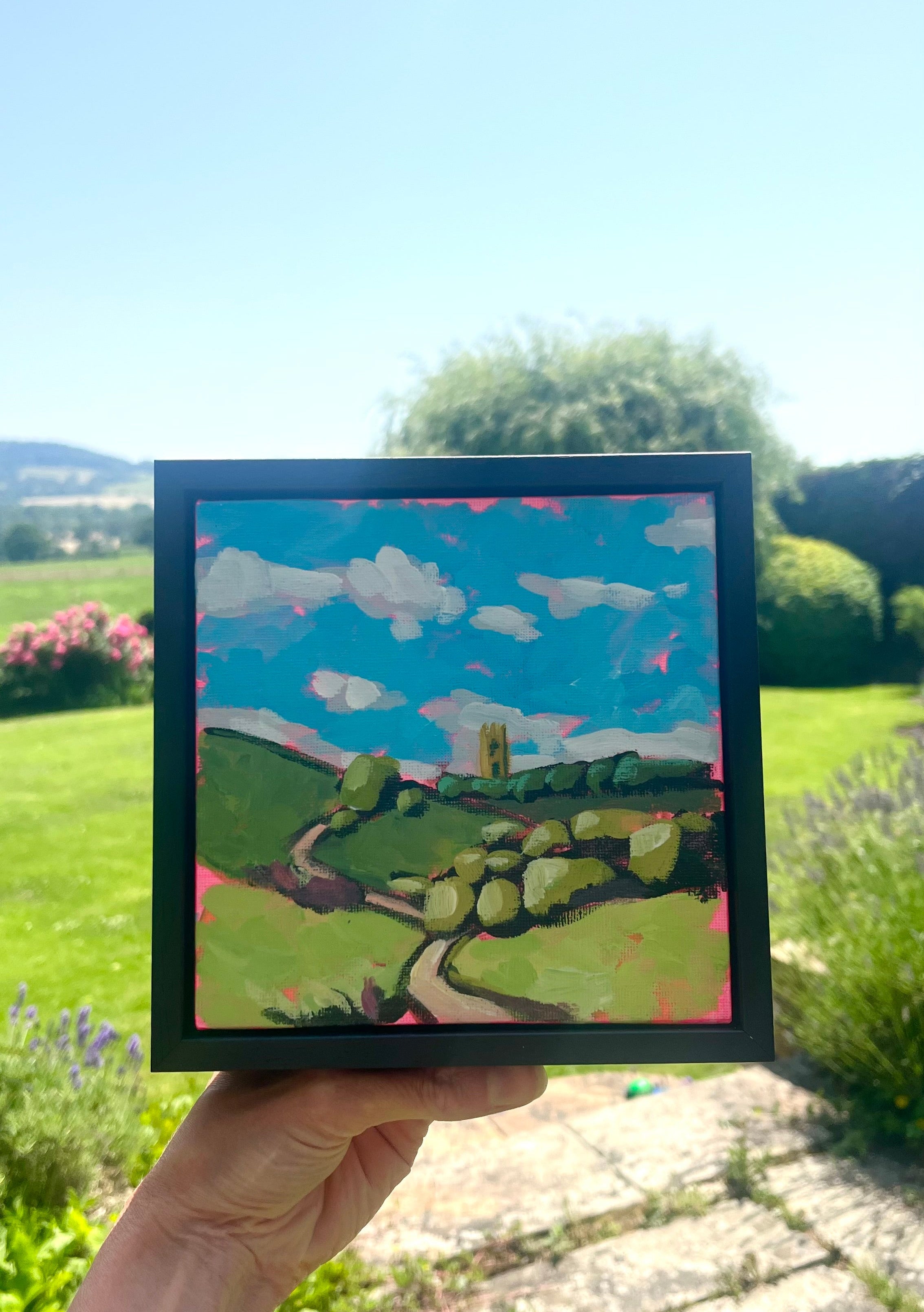 Image of a painting being held up with hill in the background