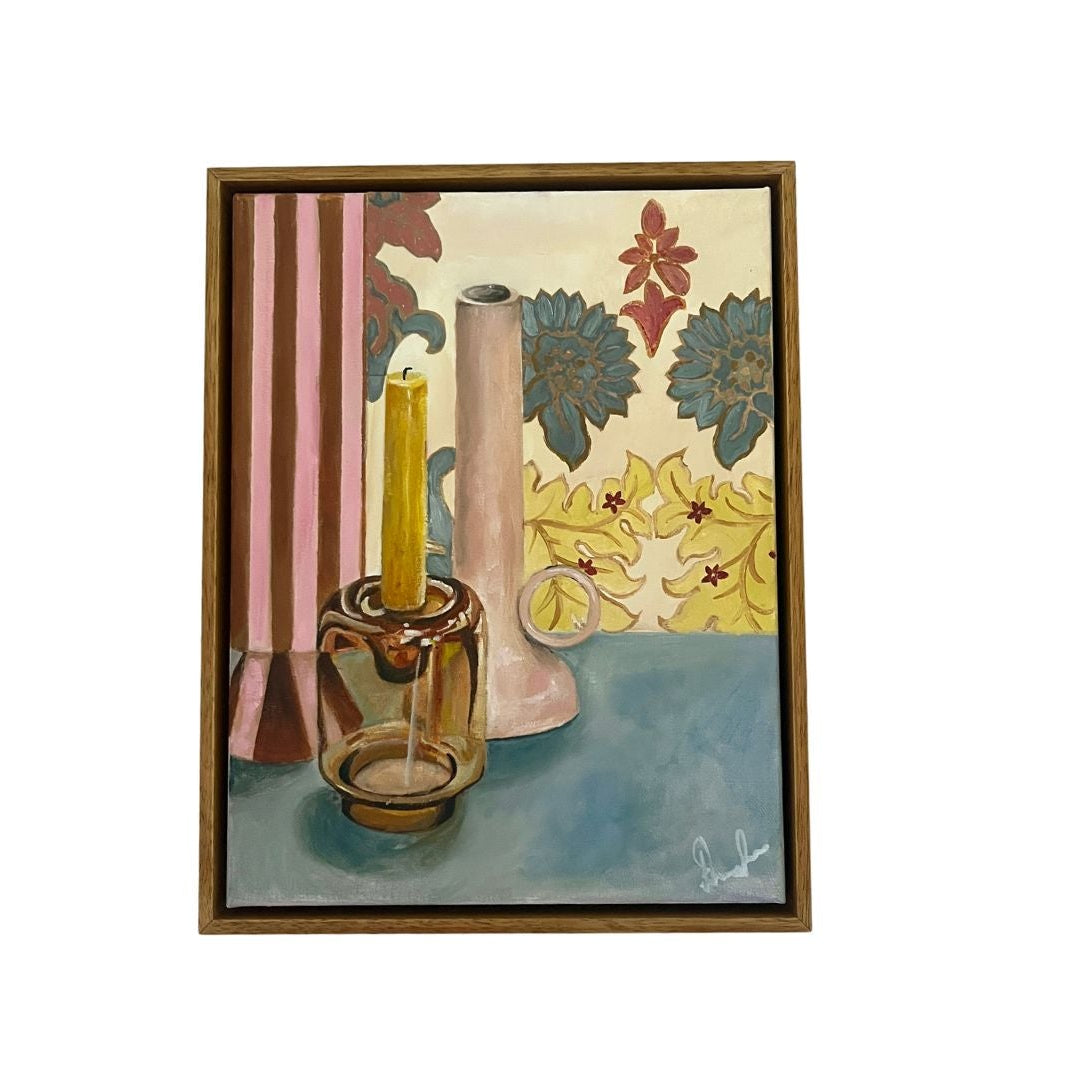 Framed artwork of a still life scene with a candle, vase, and decorative elements.