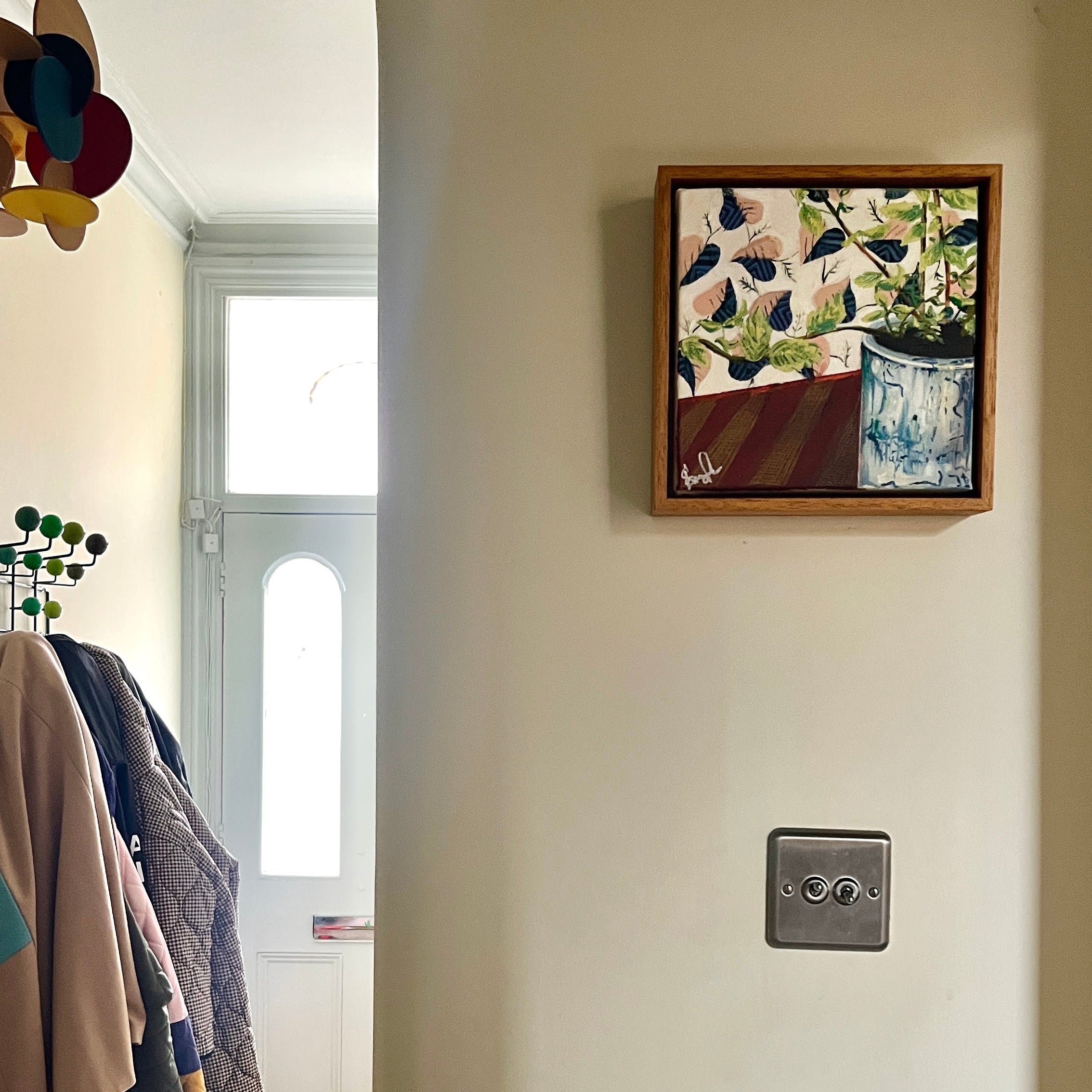 Painting of a plant on a cream wall in a hallway.