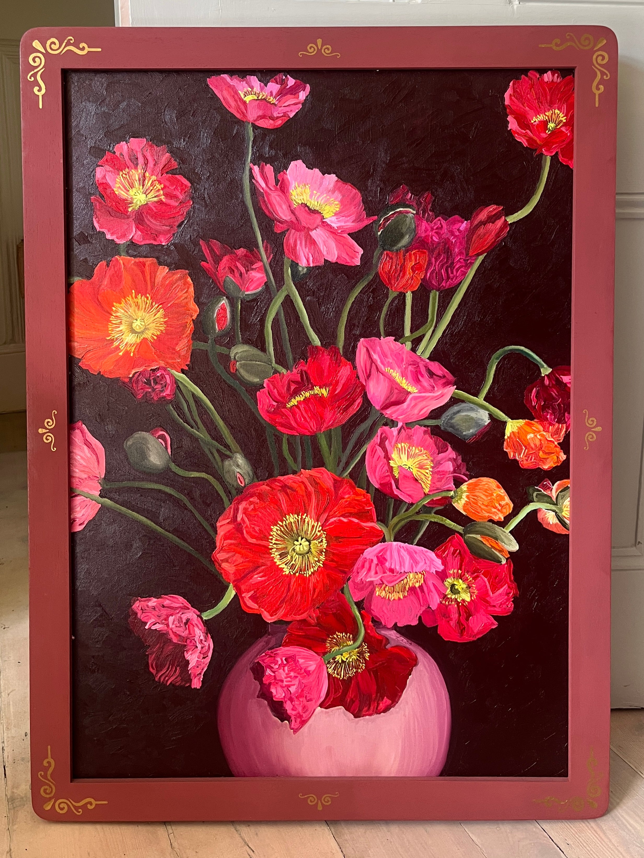 Floral painting with pink and red flowers in a vase on a dark background, framed by a decorative border.