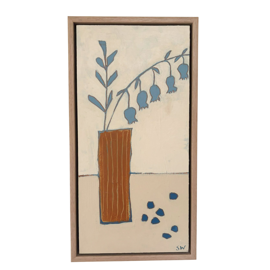 A framed minimalist painting featuring a blue bell-shaped floral branch in a brown vase against a warm cream background, with a light wood frame.