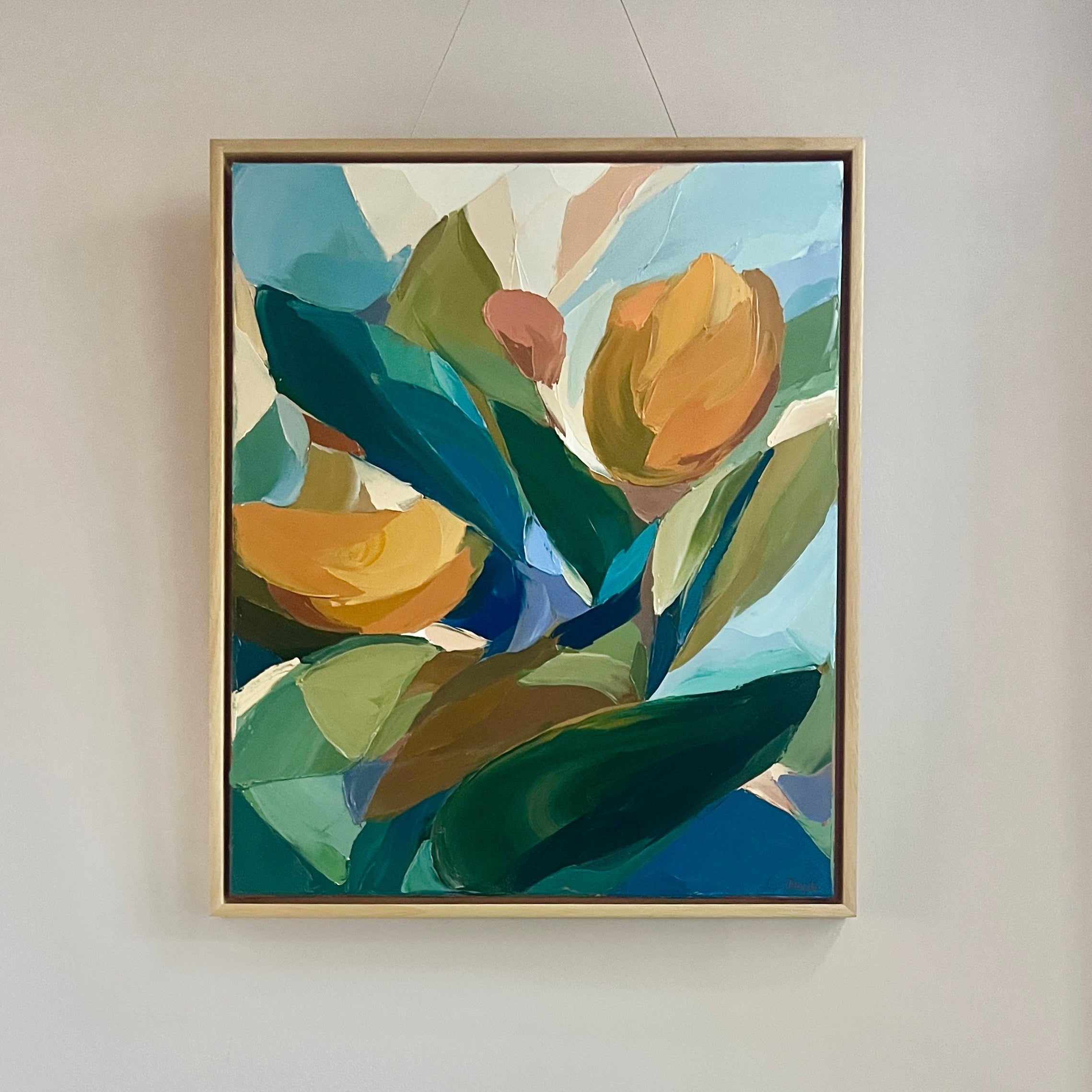 Framed abstract artwork with green and blue tones on a wall.
