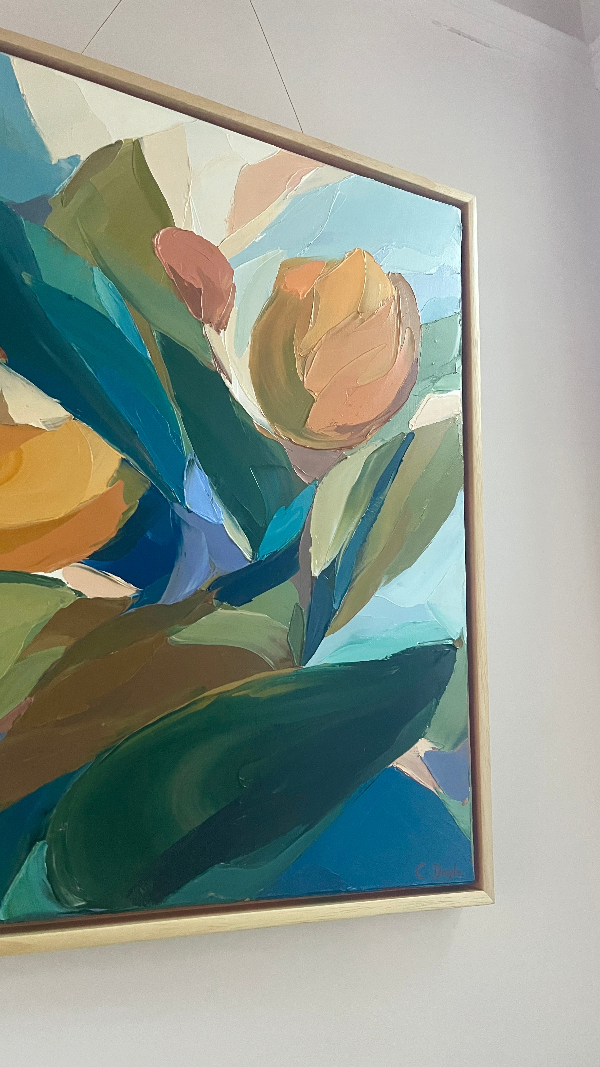 Framed abstract painting with green and blue tones on a white wall