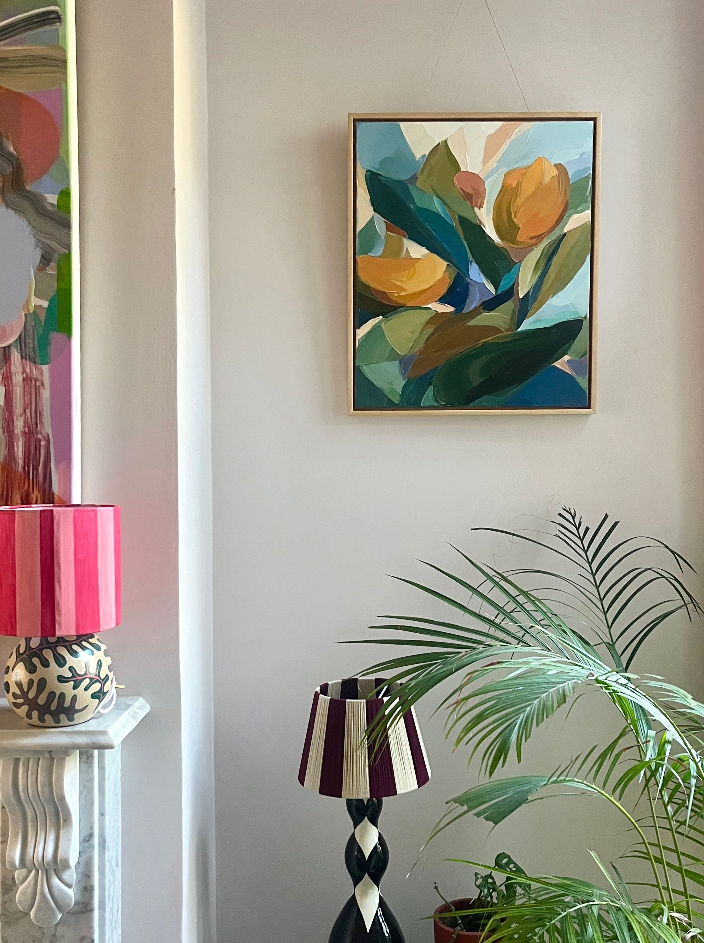 Colorful abstract art on a white wall with decorative lamps and plants.