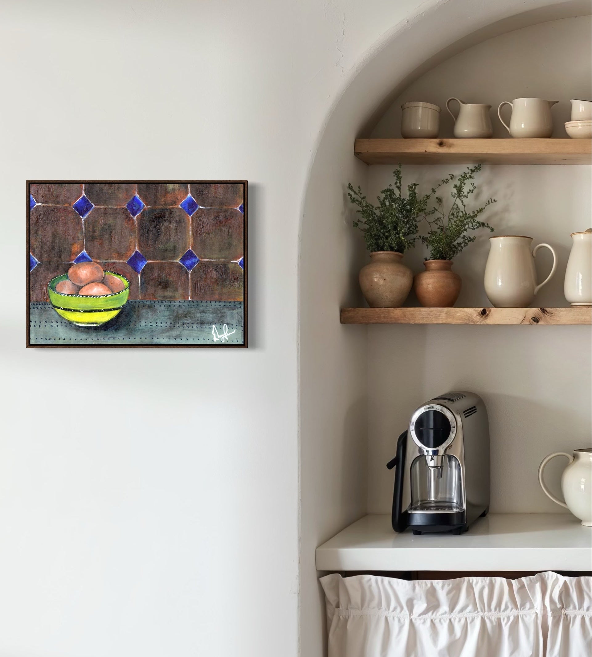 Kitchen corner with a coffee machine, shelves with mugs and plants, and a wall art piece.