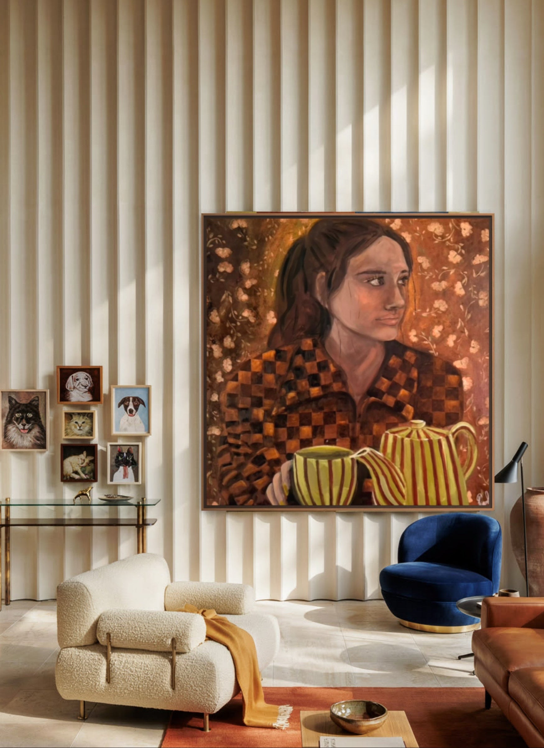 A large framed portrait painting of a woman with a striped mug hangs on a beige ribbed wall in a modern living room with a cream armchair, blue accent chair, and wood ceiling.