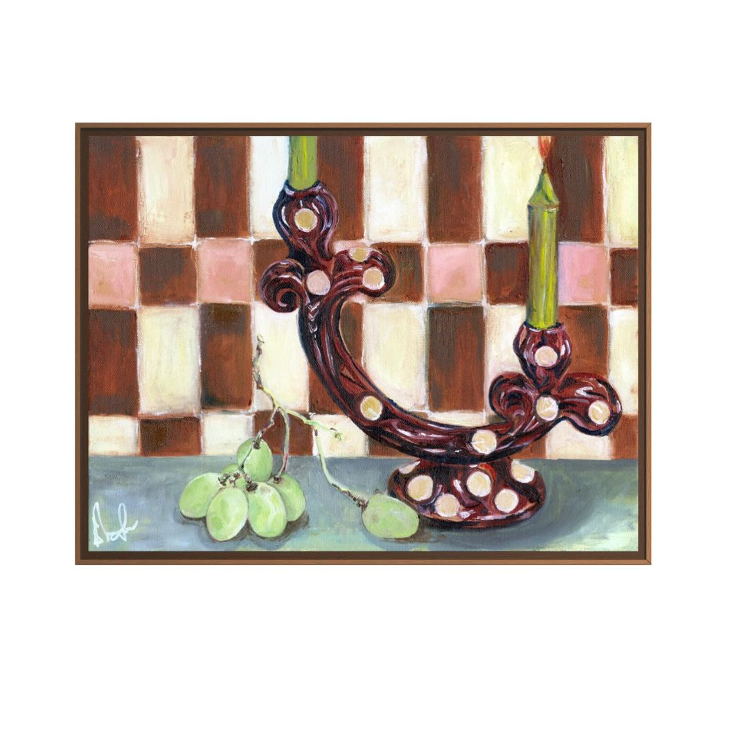 Framed artwork of a decorative candle holder with grapes on a checkered background