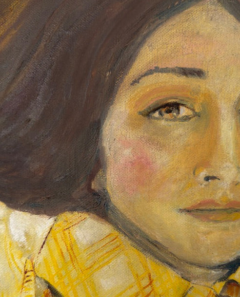 A square canvas painting of a woman's face in a close-up portrait, showing dark brown hair, a pale face with pinkish cheeks, and a yellow plaid shirt, displayed against a light gray wall.