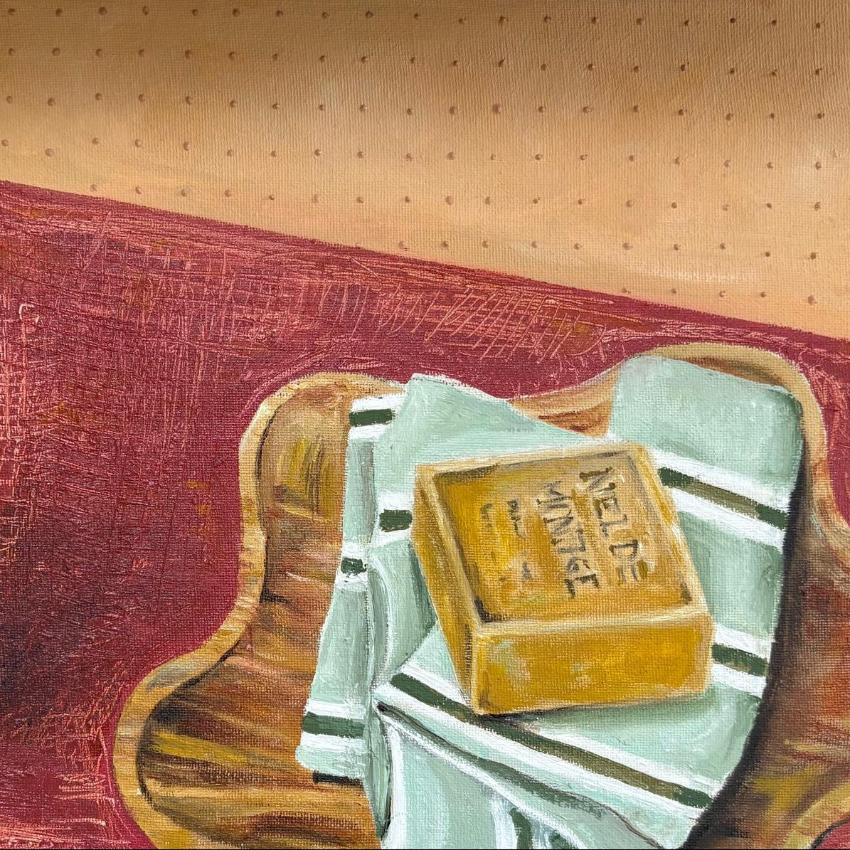 Bar of soap sat on a cloth and wooden tray. Red table cloths and textured wallpaper 