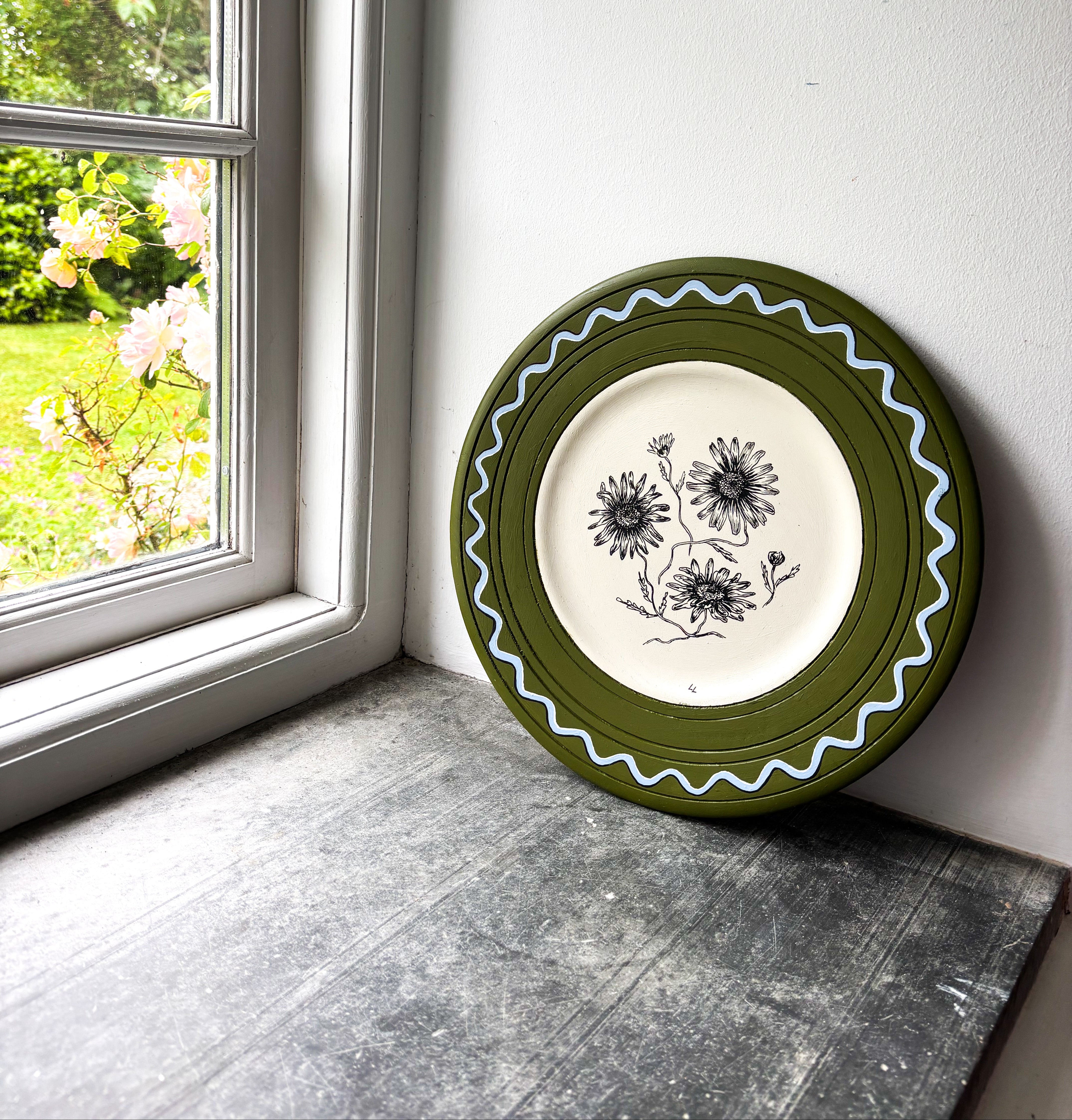 Green plate with pen and ink daisy inside