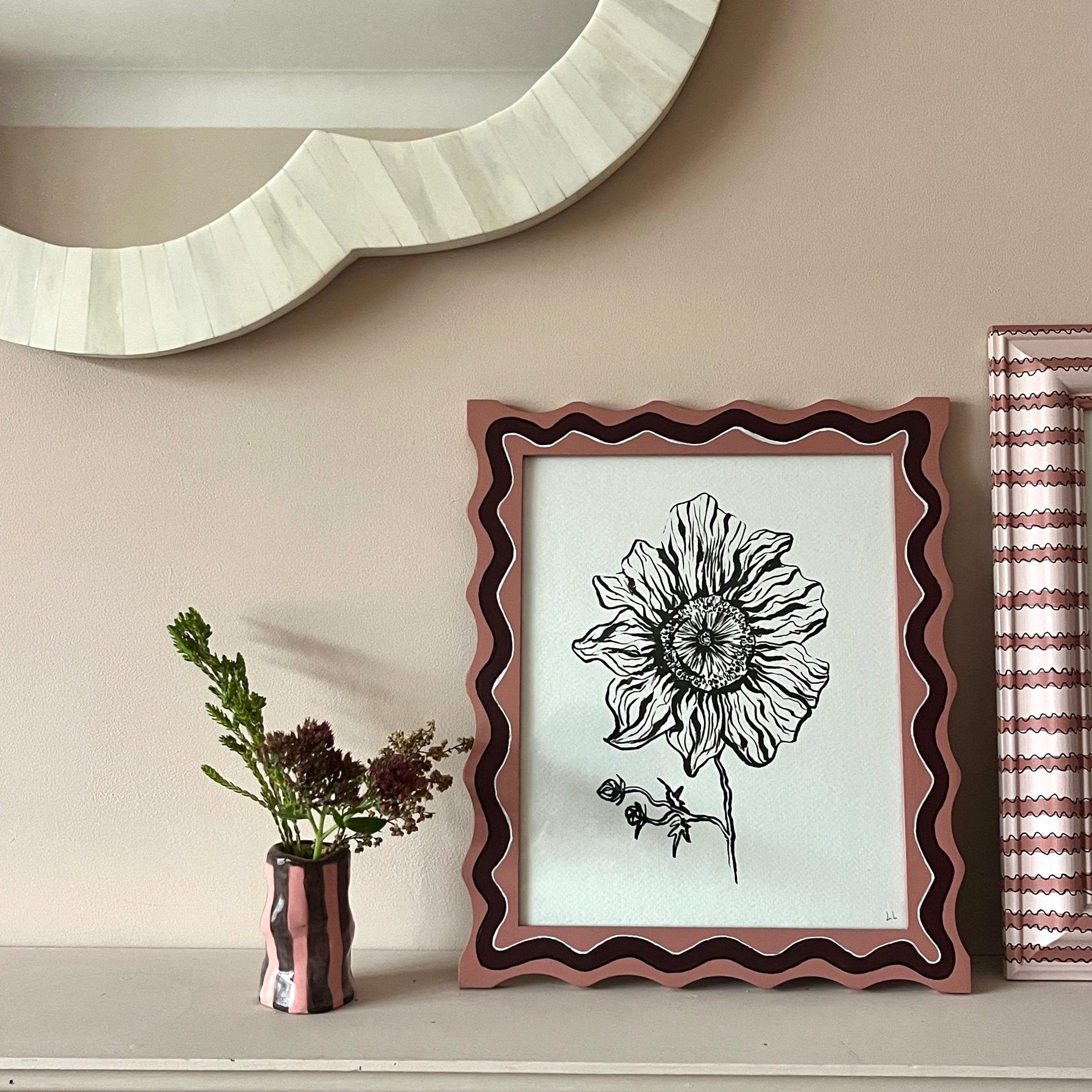 Decorative wall with framed artwork, mirror, and small plant.