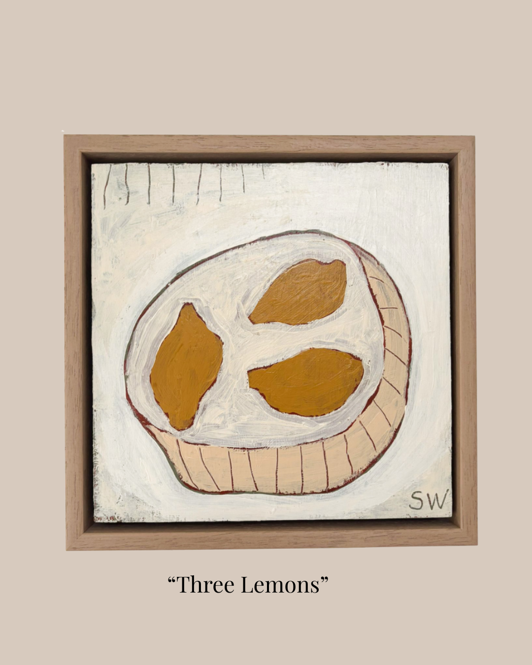 A framed painting titled "Three Lemons" showing three yellow-orange lemons on an off-white background, enclosed in a light brown wooden frame against a beige backdrop with the title printed below.
