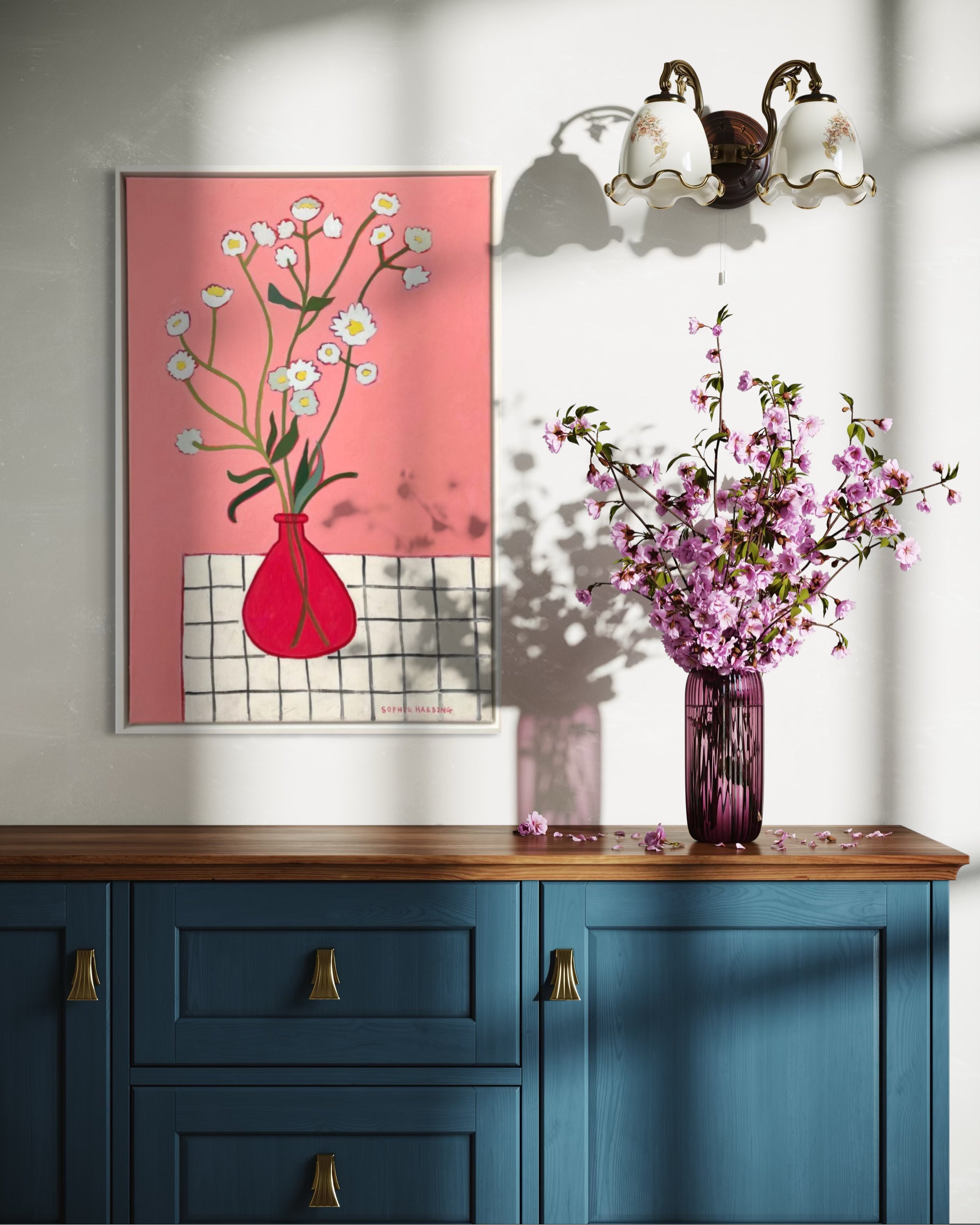 Decorative setup with a pink floral painting, blue cabinet, and purple vase with flowers.