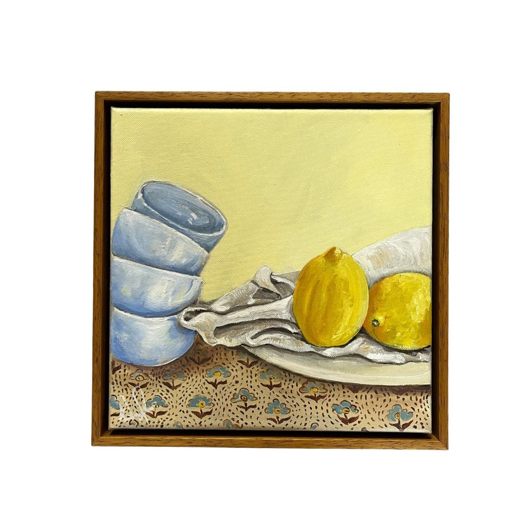 Emma Gurner canvas showing still life of stacked cups on a plate with lemons on a a printed table cloth