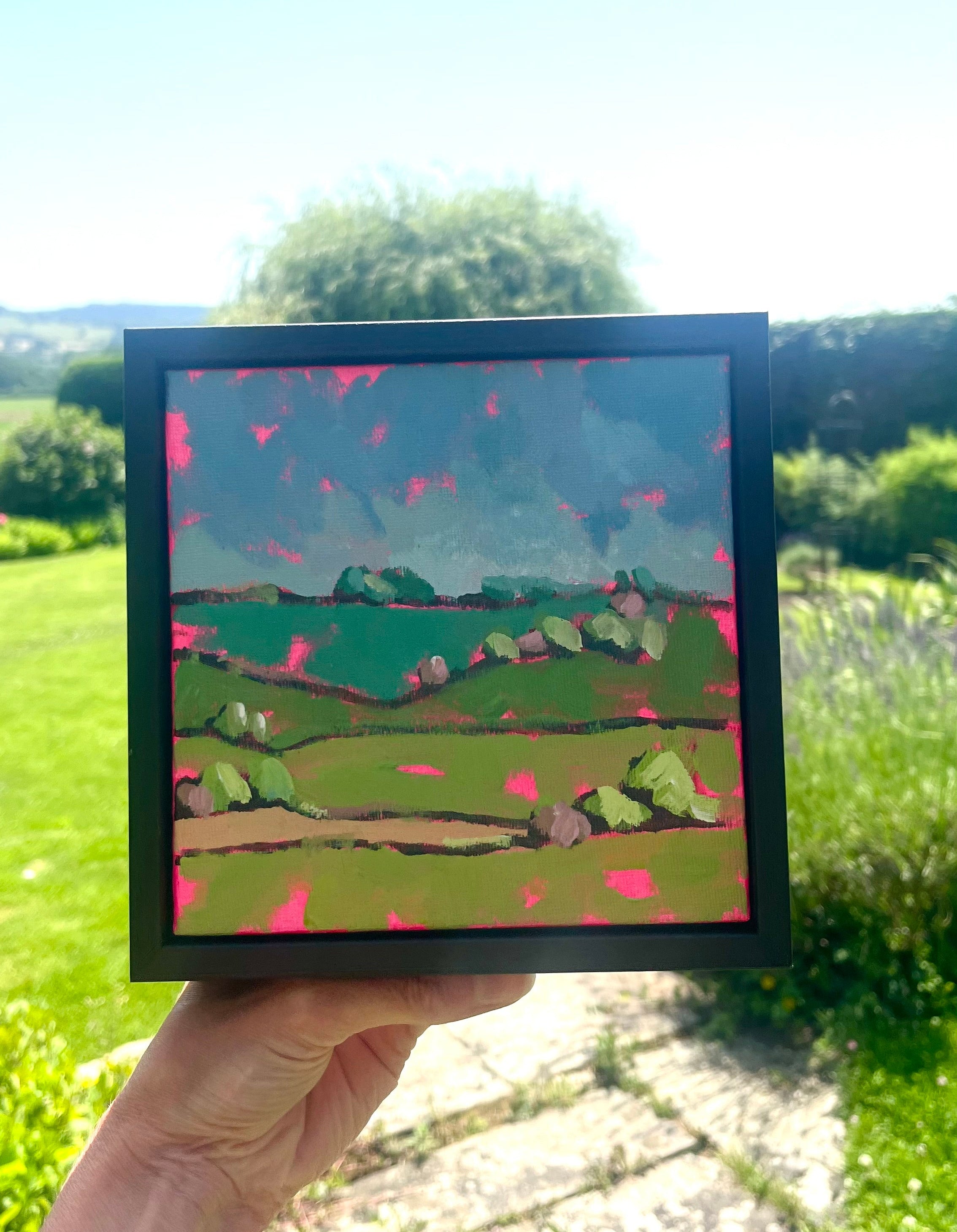 images of a canvas being held outside with green hills in the background.