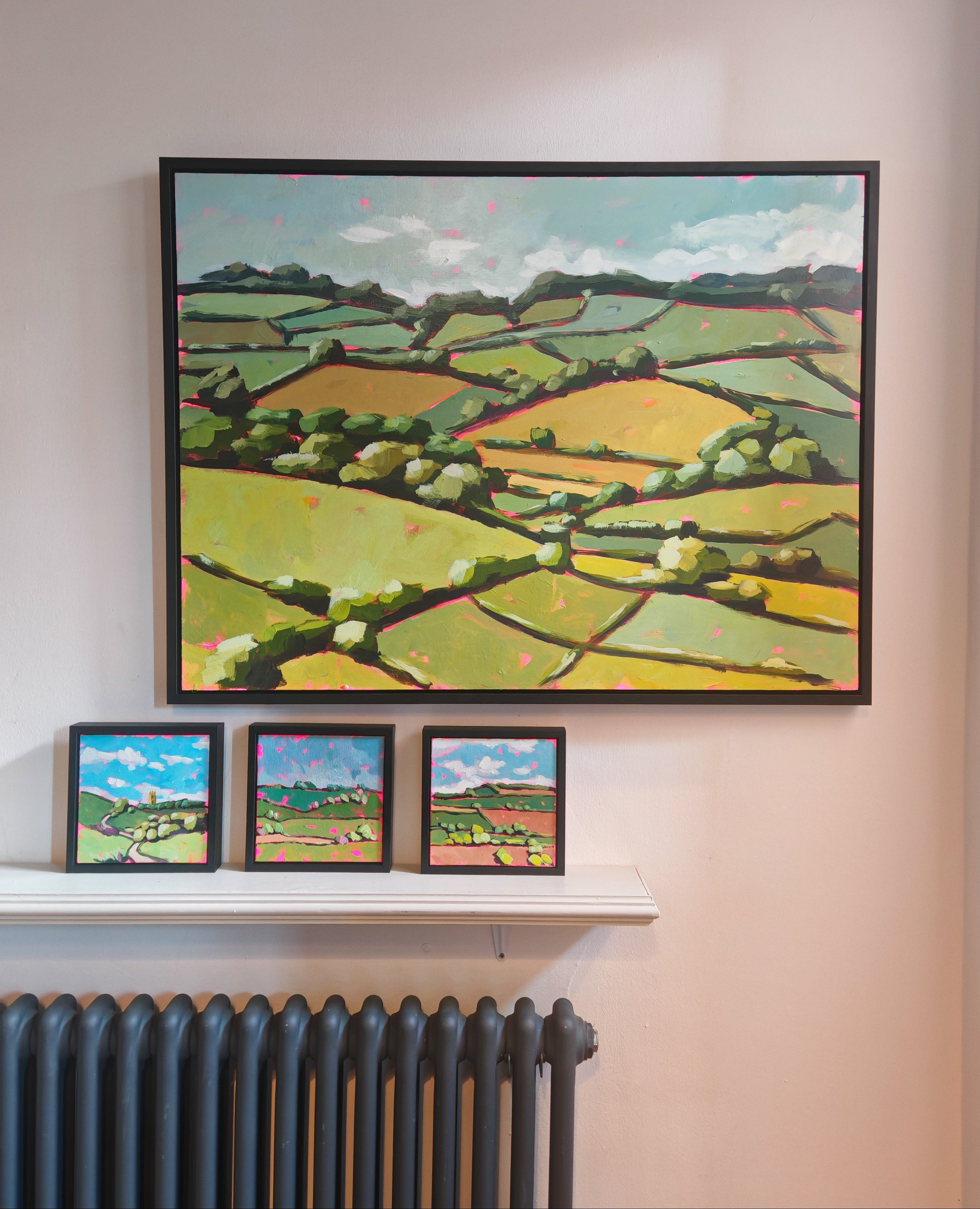 Framed landscape paintings on a wall above a radiator