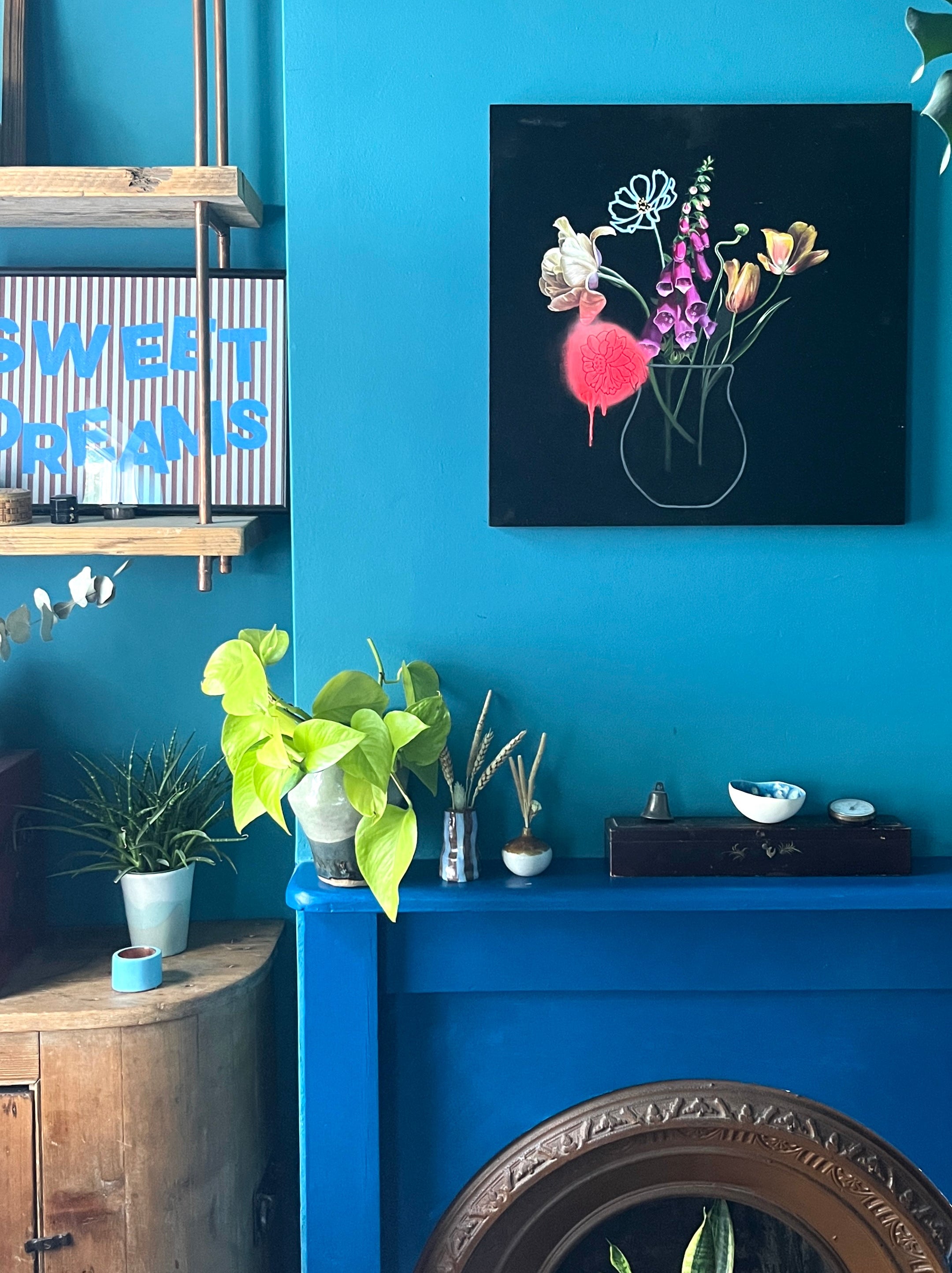 Still life painting with black background on wall in a blue room 