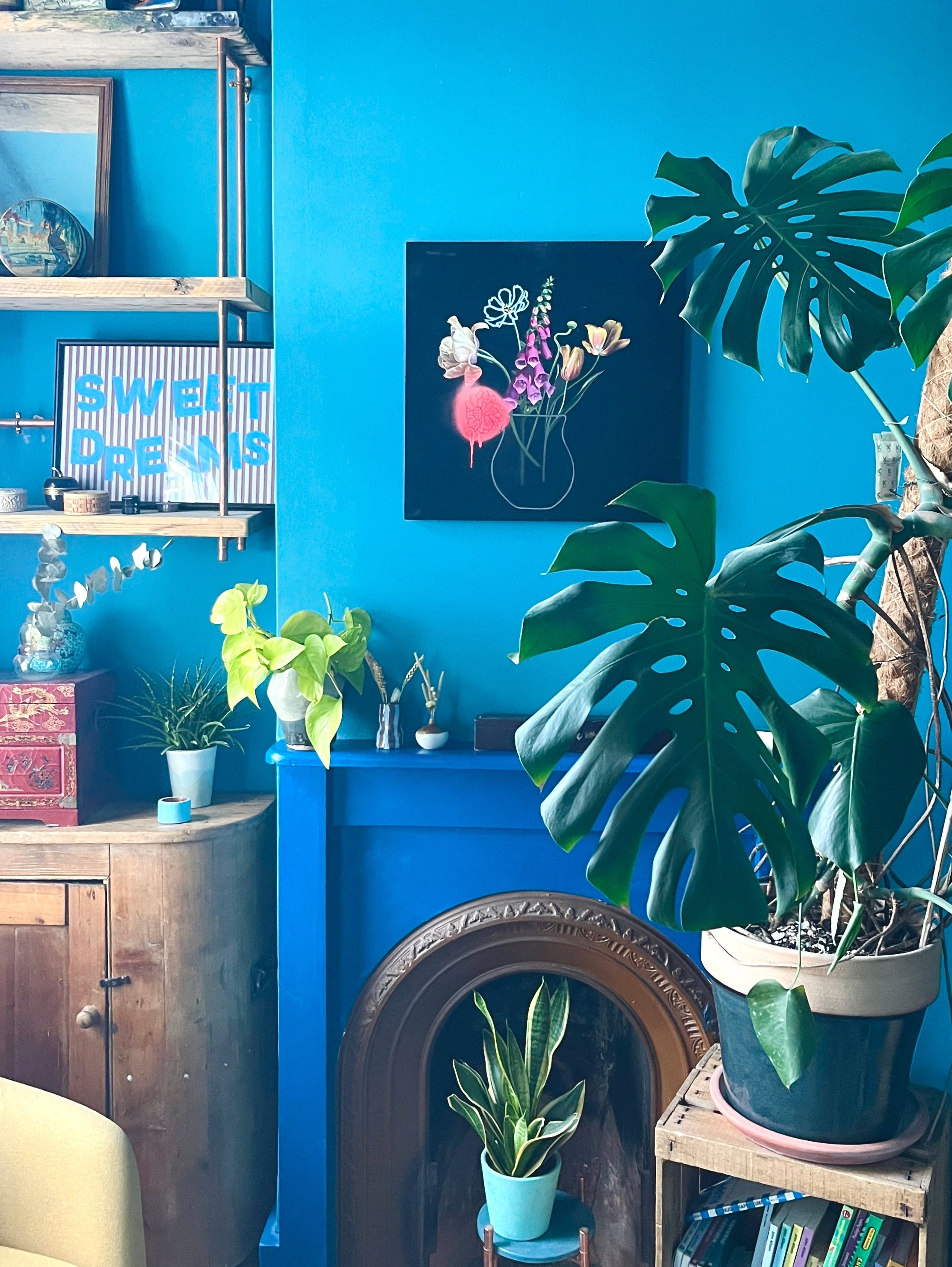 Still life painting in a blue room above a fireplace  with plants. 