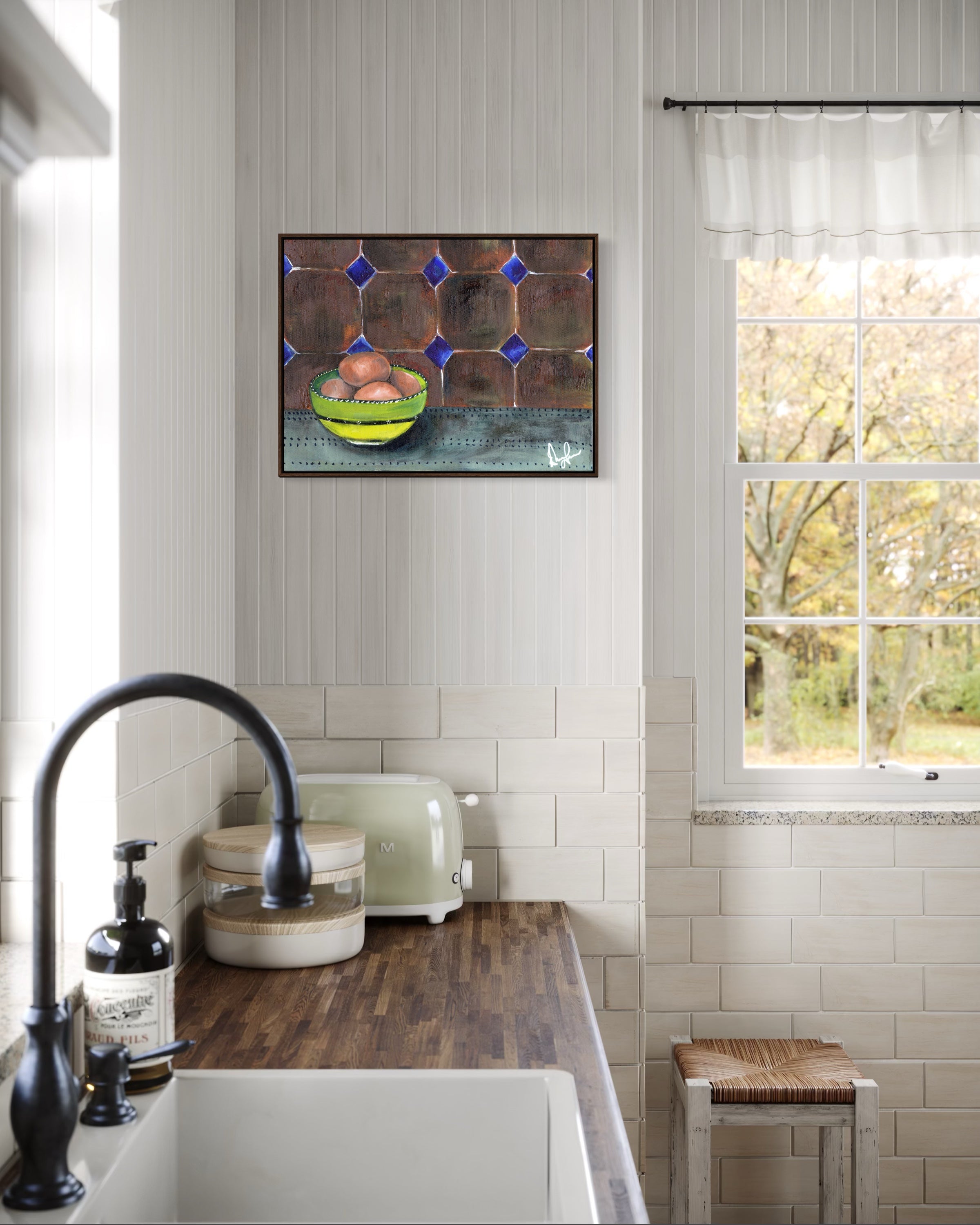 Kitchen interior with a painting of a bowl of fruit on the wall above a sink.