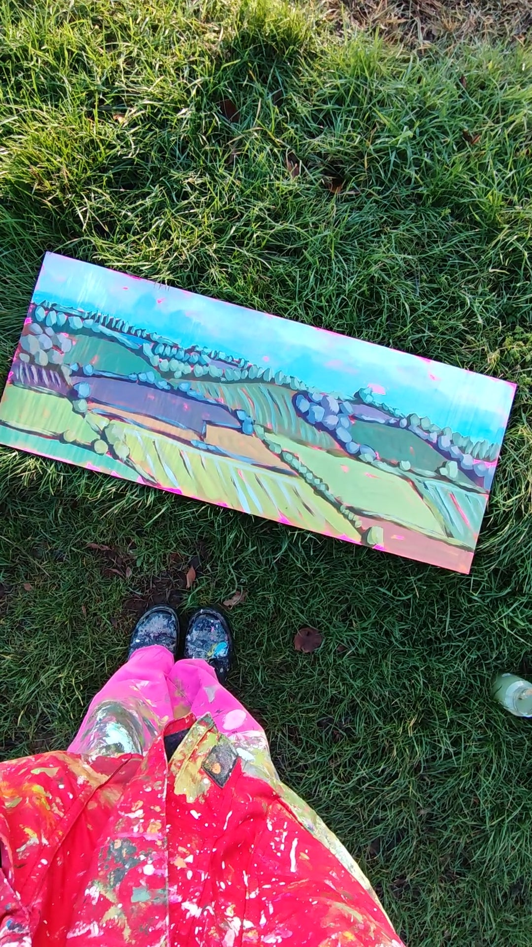Woman looking at painting on grass. 
