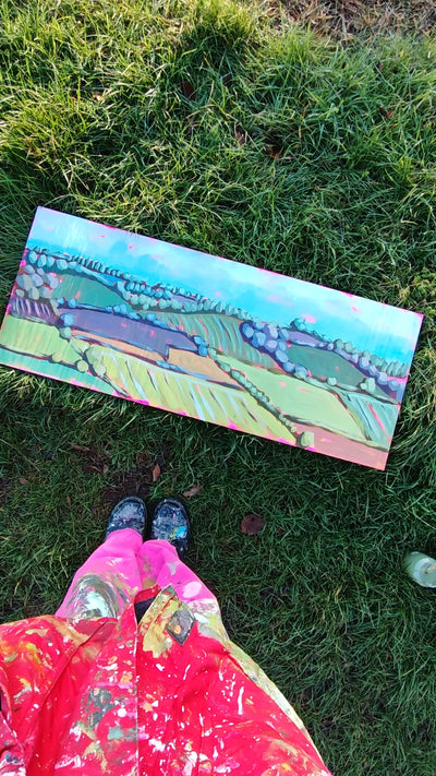 Woman looking at painting on grass. 