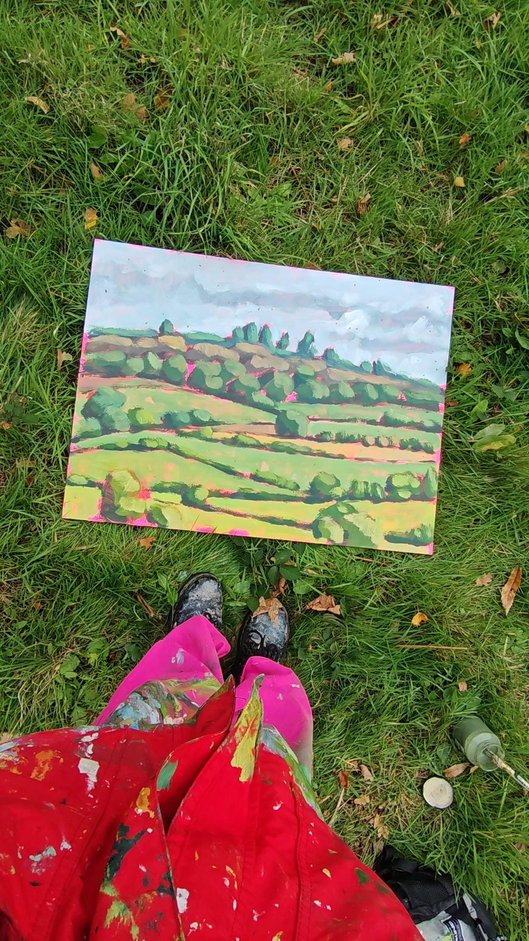 Video of a person legs standing above artwork on the grass 